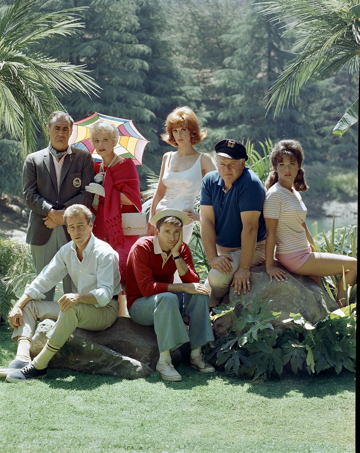 The 'Gilligan's Island' cast dressed as their characters and posing on an island set for a promotional photo.