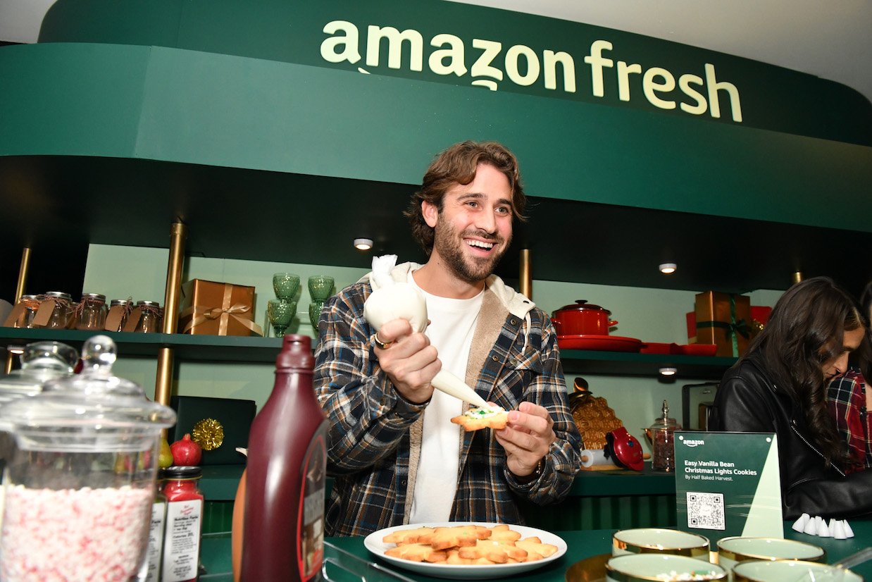 Greg Grippo smiling and holding food while at an Amazon event. He arrives on the set of the 'Bachelor in Paradise' Season 8 reunion