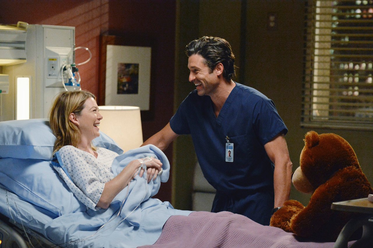 Ellen Pompeo as Meredith Grey holds a newborn baby in the hospital and Patrick Dempsey as Derek Shepherd stands beside her in 'Grey's Anatomy'.