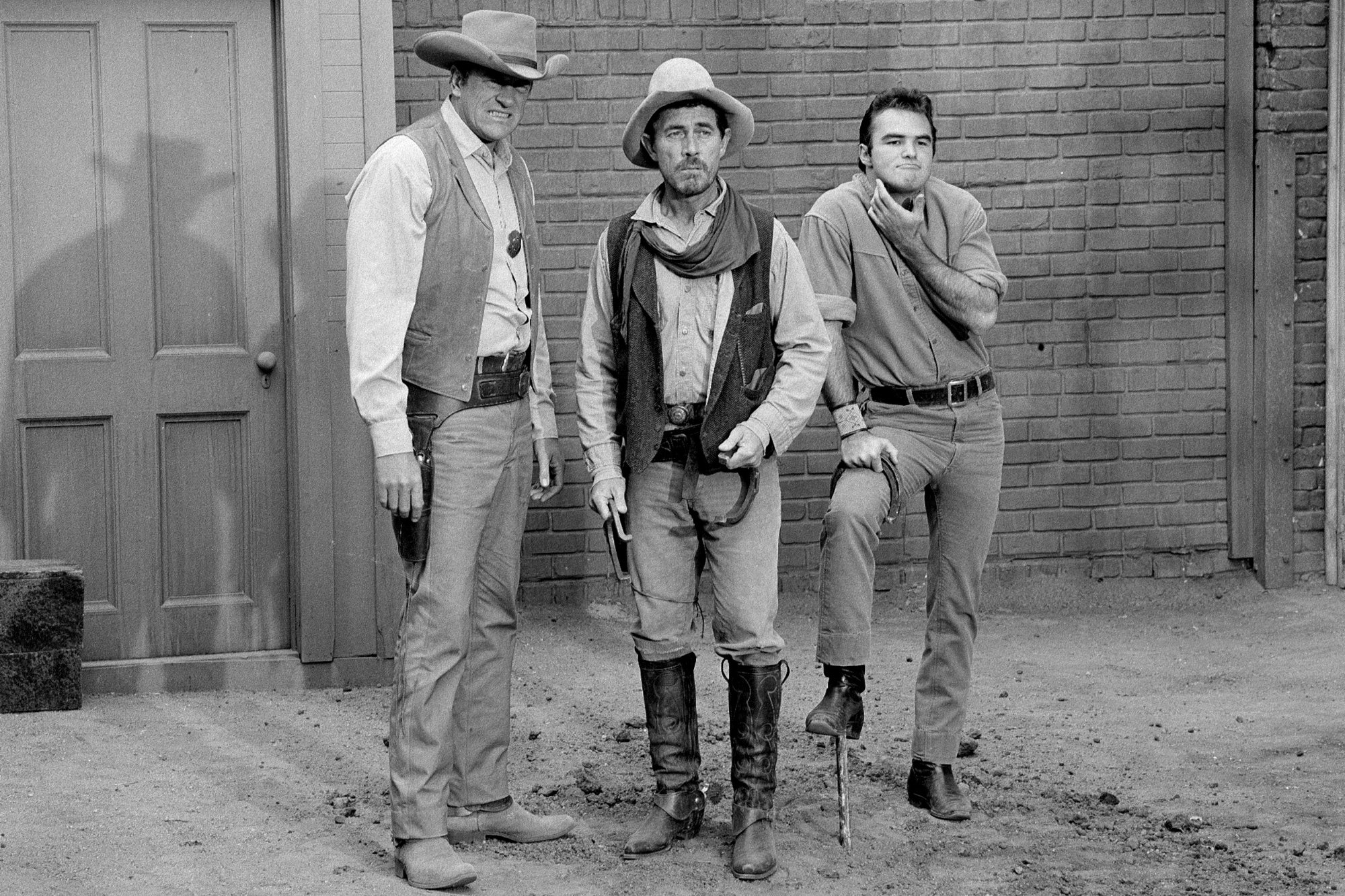 'Gunsmoke' James Arness as Matt Dillon, Ken Curtis as Festus Haggen, and Burt Reynolds as Quint Asper. They're standing in front of an old Western building making funny faces.