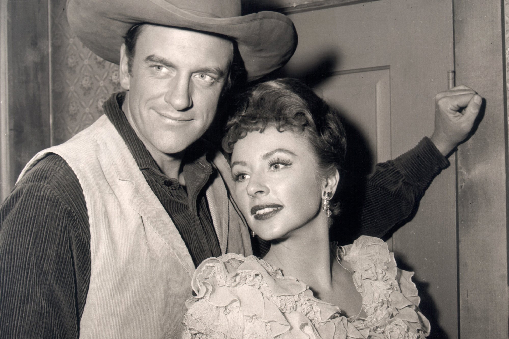 'Gunsmoke' James Arness as Matt Dillon and Amanda Blake as Kitty Russell. Arness is smiling with his arm resting on the door behind Blake.