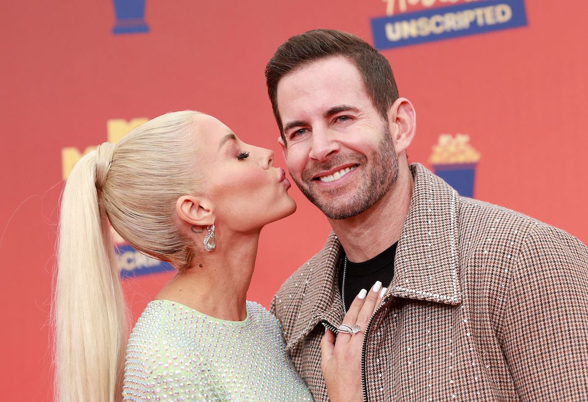Heather Rae Young and Tarek El Moussa, who love giving eeach other gifts, pose on a red carpet together with Heather kissing Tarek's cheek.