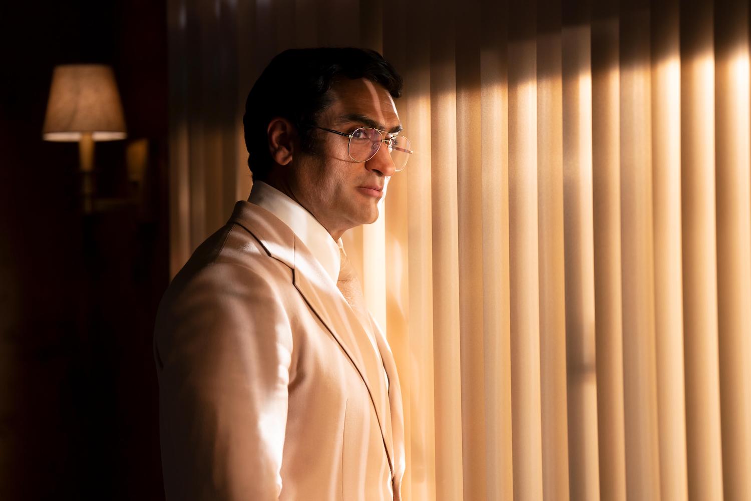 The Hulu Original 'Welcome to Chippendales' stars Kumail Nanjiani as Somen "Steve" Bannerjee and is seen here standing in front of blinds with shadows on his face in a production still.