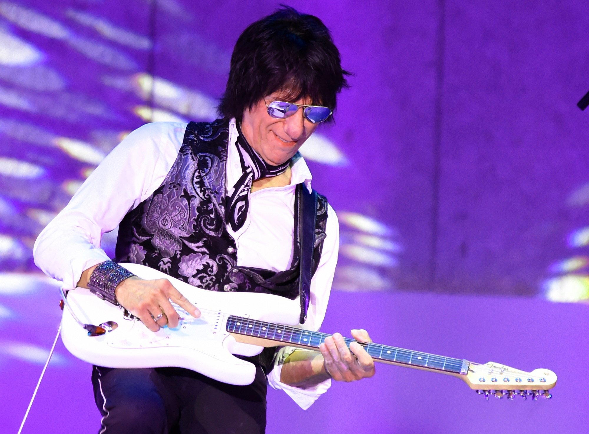 Jeff Beck plays a white electric guitar on stage
