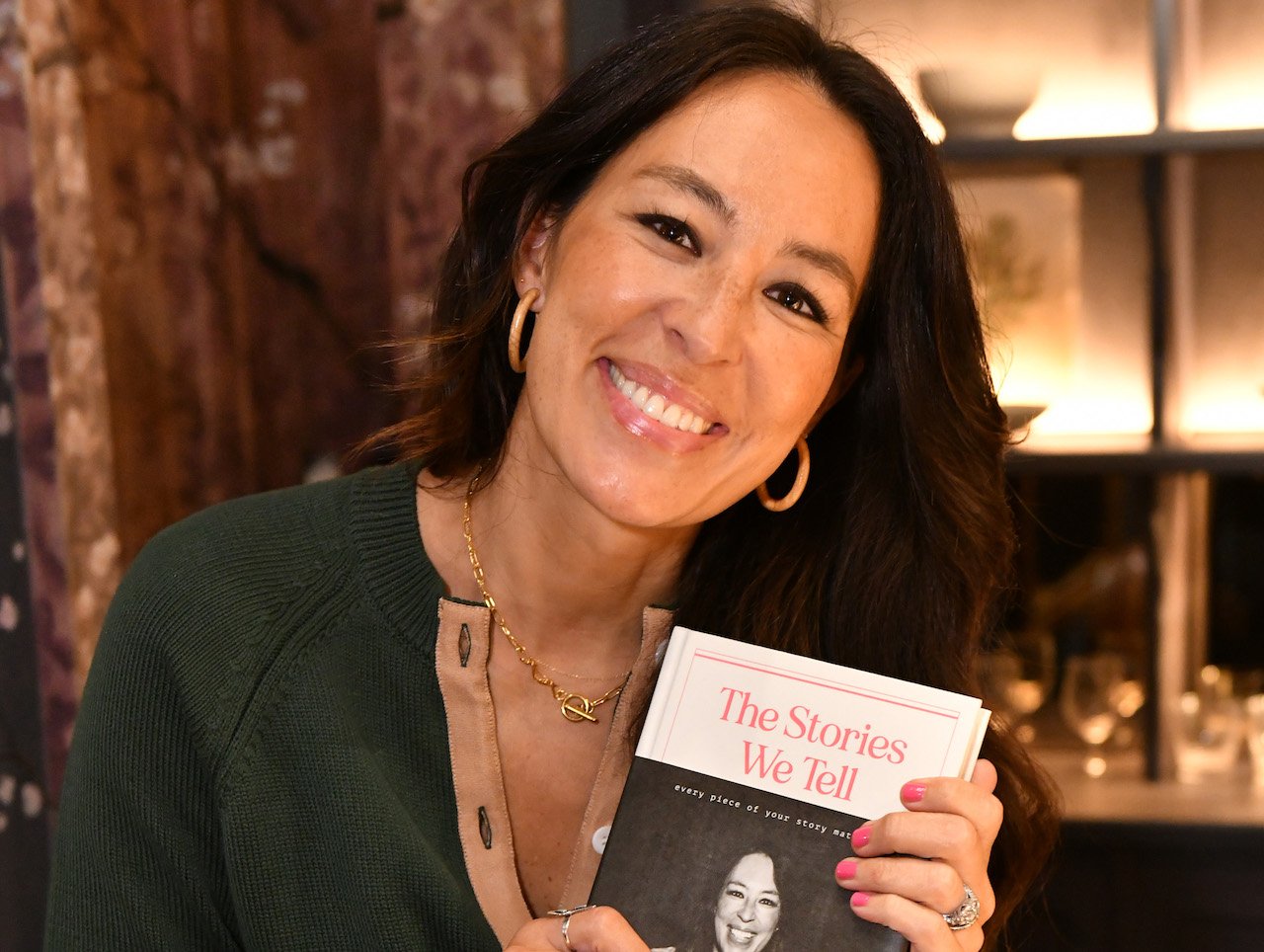 Joanna Gaines smiles and holds a copy of her memoir, 'The Stories We Tell,' during her book launch.