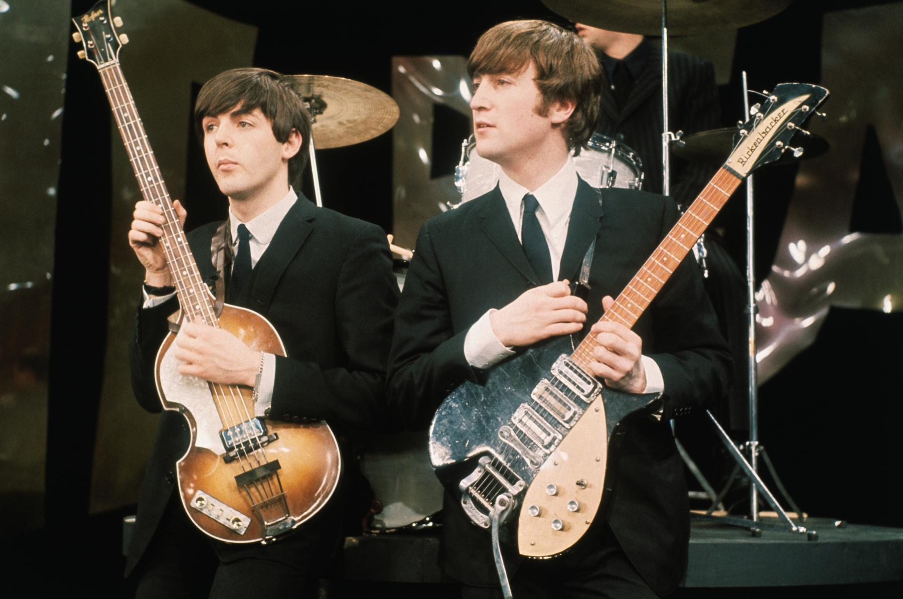 Paul McCartney and John Lennon of The Beatles hold their guitars while on the set of 'The Ed Sullivan Show'
