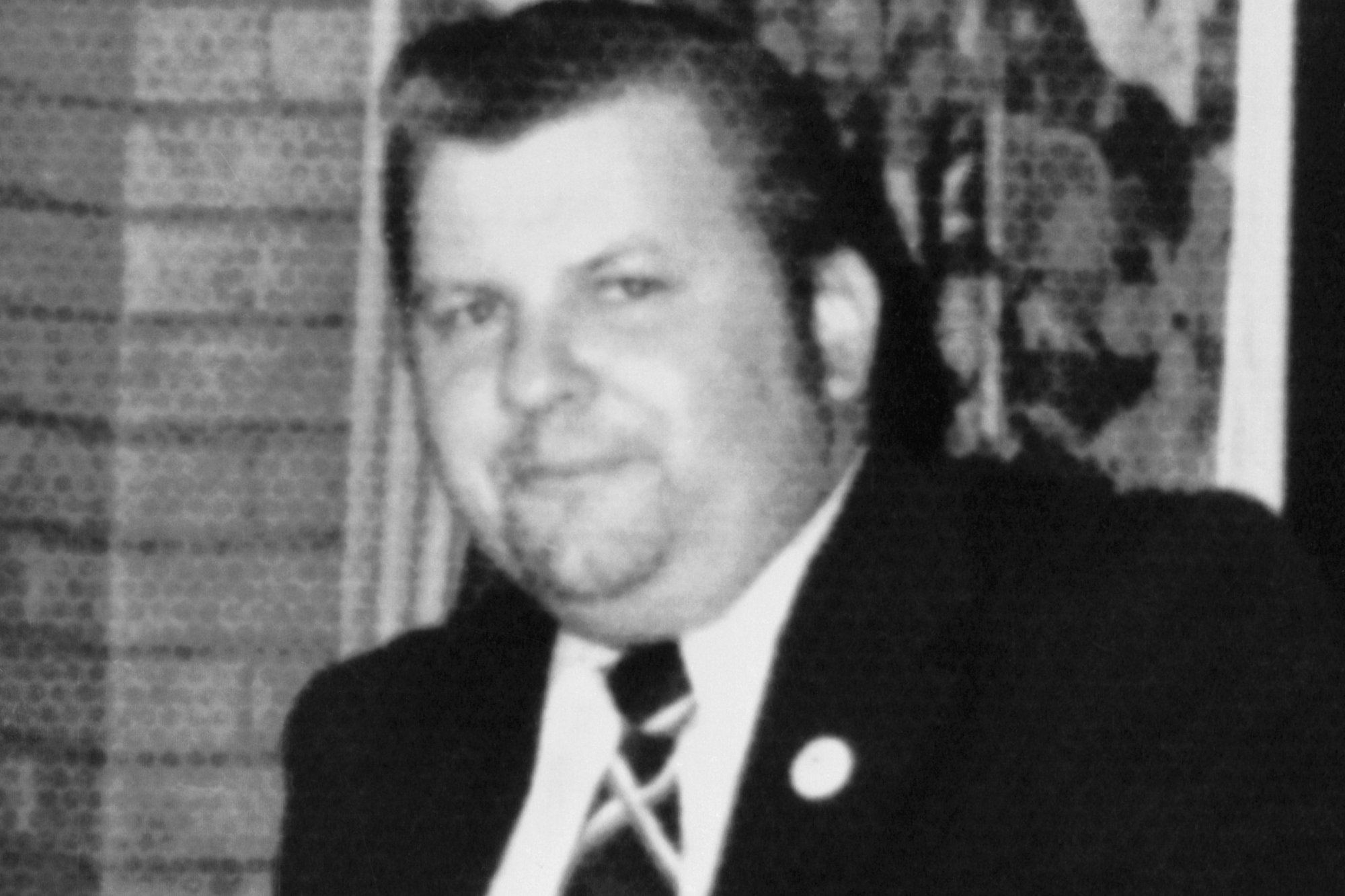 John Wayne Gacy, who had 29 bodies at his residence. He's wearing a suit and tie in a black-and-white photograph looking at the camera.