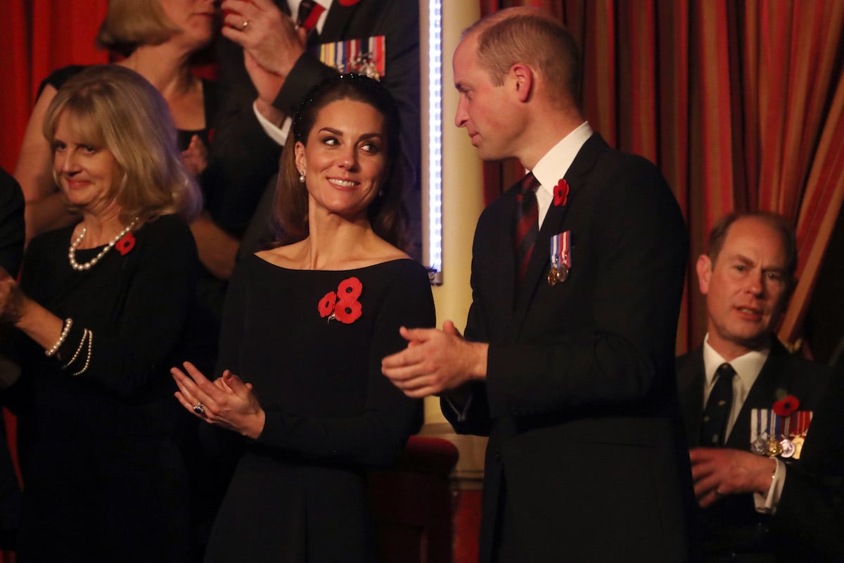 Kate Middleton and Prince William, who appeared 'happier' than Prince Harry and Meghan Markle at the 2019 Festival of Remembrance, according to a body language expert, clap and look at each other