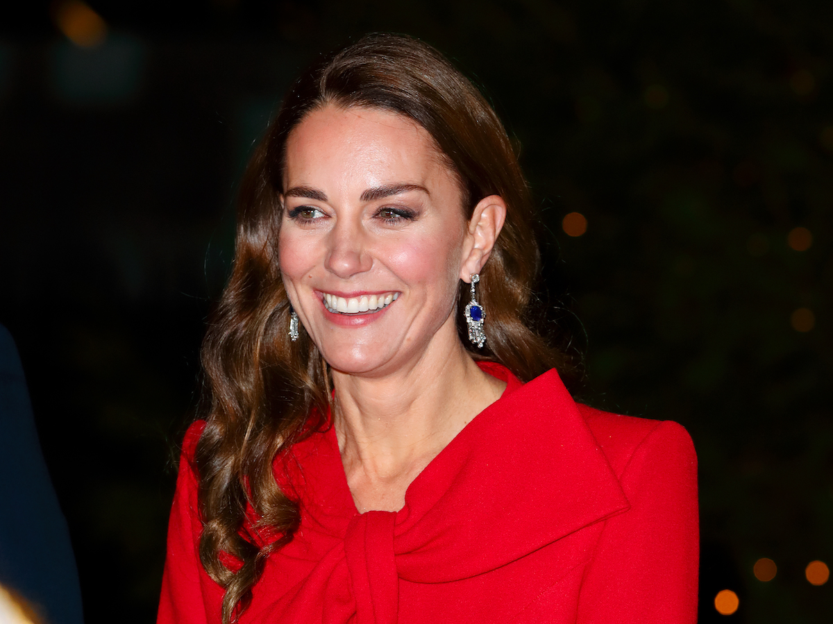 Kate Middleton, who is having a 2022 Christmas carol concert at Westminster Abbey, smiles wearing a red coat during the 2021 Christmas carol concert event