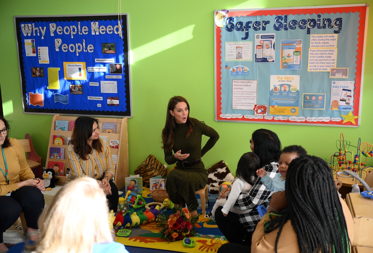 Kate Middleton, whose tone of voice didn't change when she spoke to a 3-year-old child on Nov. 9, 2022, according to a body language expert, talks with a group of people at a children's center