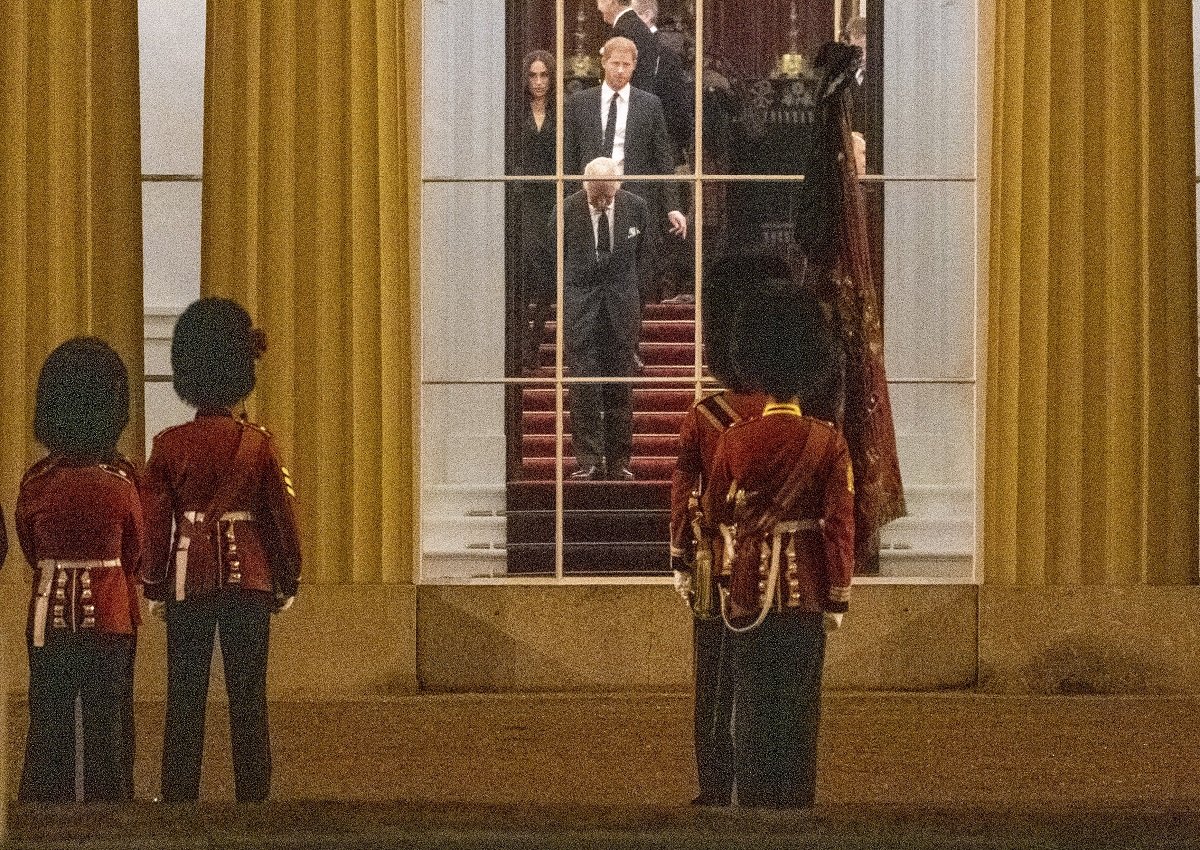 King Charles III, Prince Harry, and Meghan Markle inside Buckingham Palace as they await the Royal Hearse carrying Queen Elizabeth II's coffin to arrive