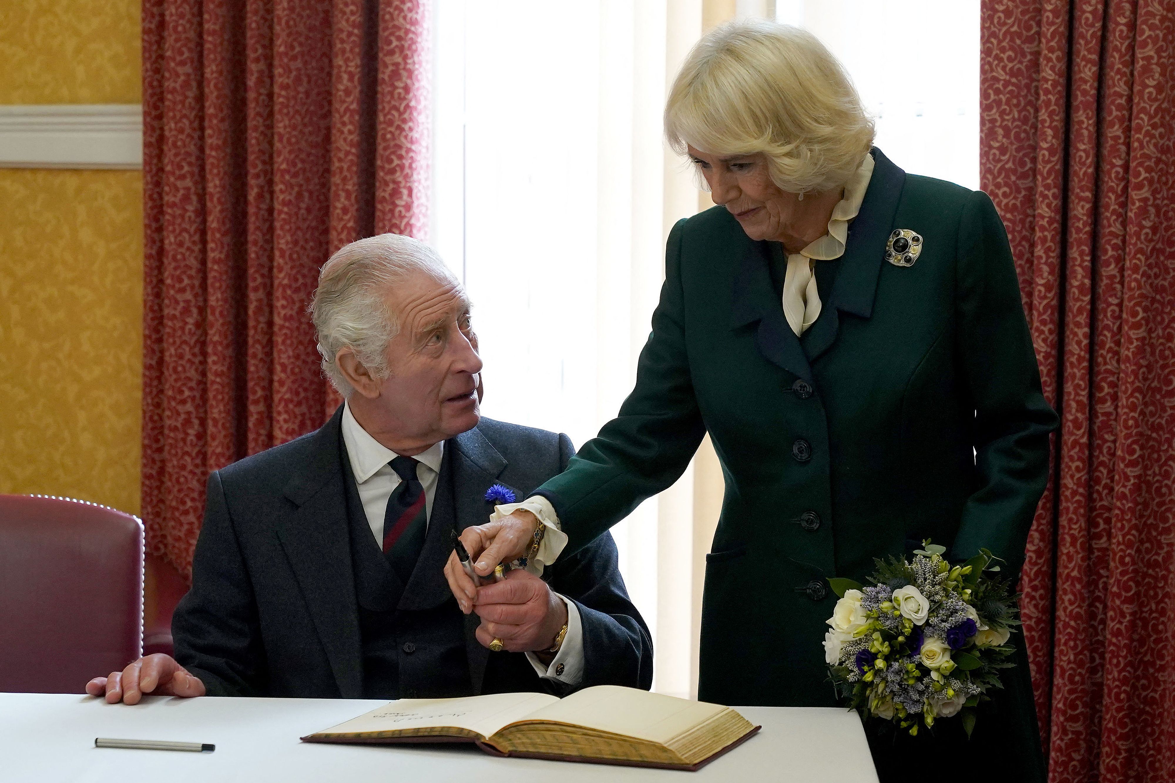 King Charles III and Camilla Parker Bowles sign a visitors' book after attending an official council meeting