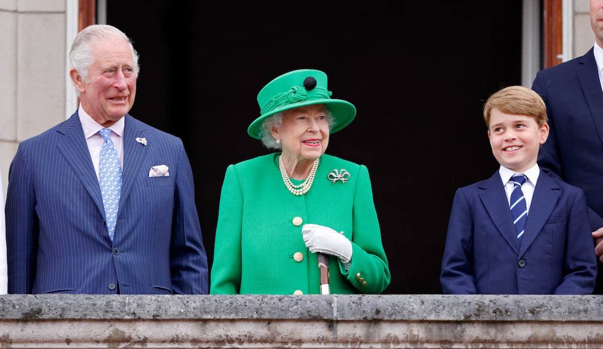King Charles, who held Prince George awkwardly in a 2018 70th birthday portrait, according to a body language expert, stands next to Queen Elizabeth and Prince George during Platinum Jubilee weekend in June 2022.