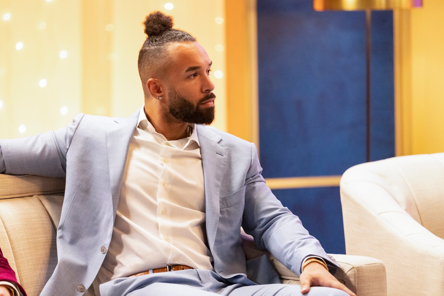 'Love Is Blind' star Bartise Bowden wears a blue suit while sitting on a couch at the reunion.