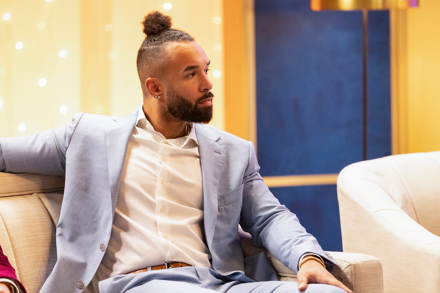 'Love Is Blind' star Bartise Bowden wears a blue suit while sitting on a couch at the reunion. The women accused Bartise of going on a date with another woman the day after his wedding.