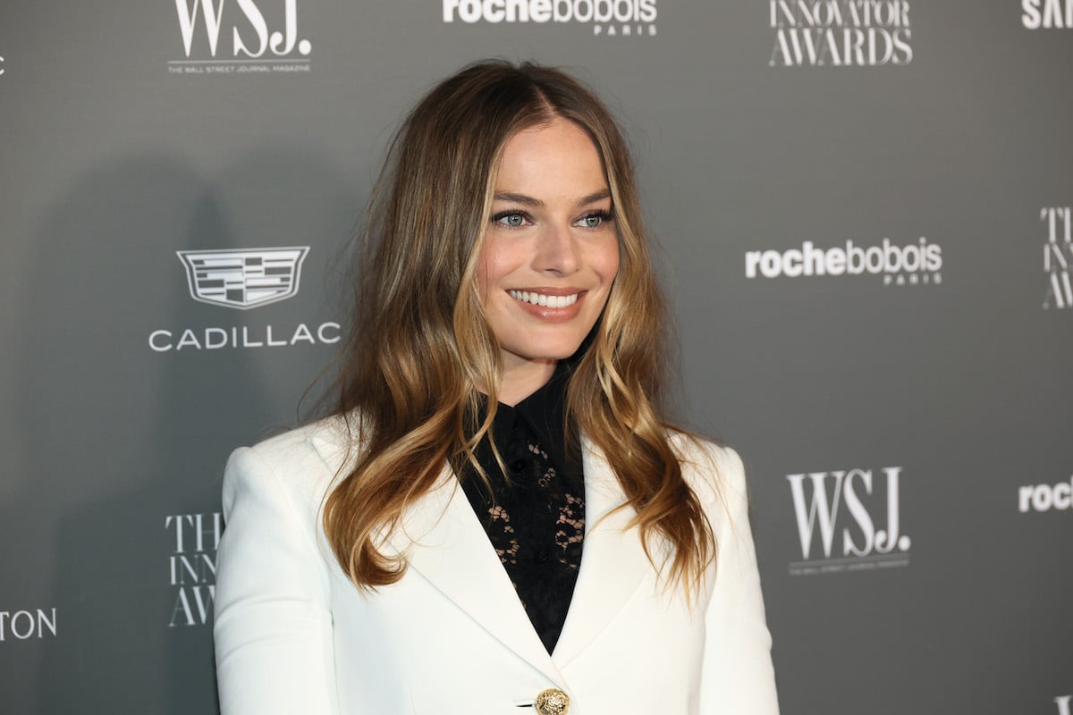 The Wolf of Wall Street alum Margot Robbie smiles while wearing a white blazer