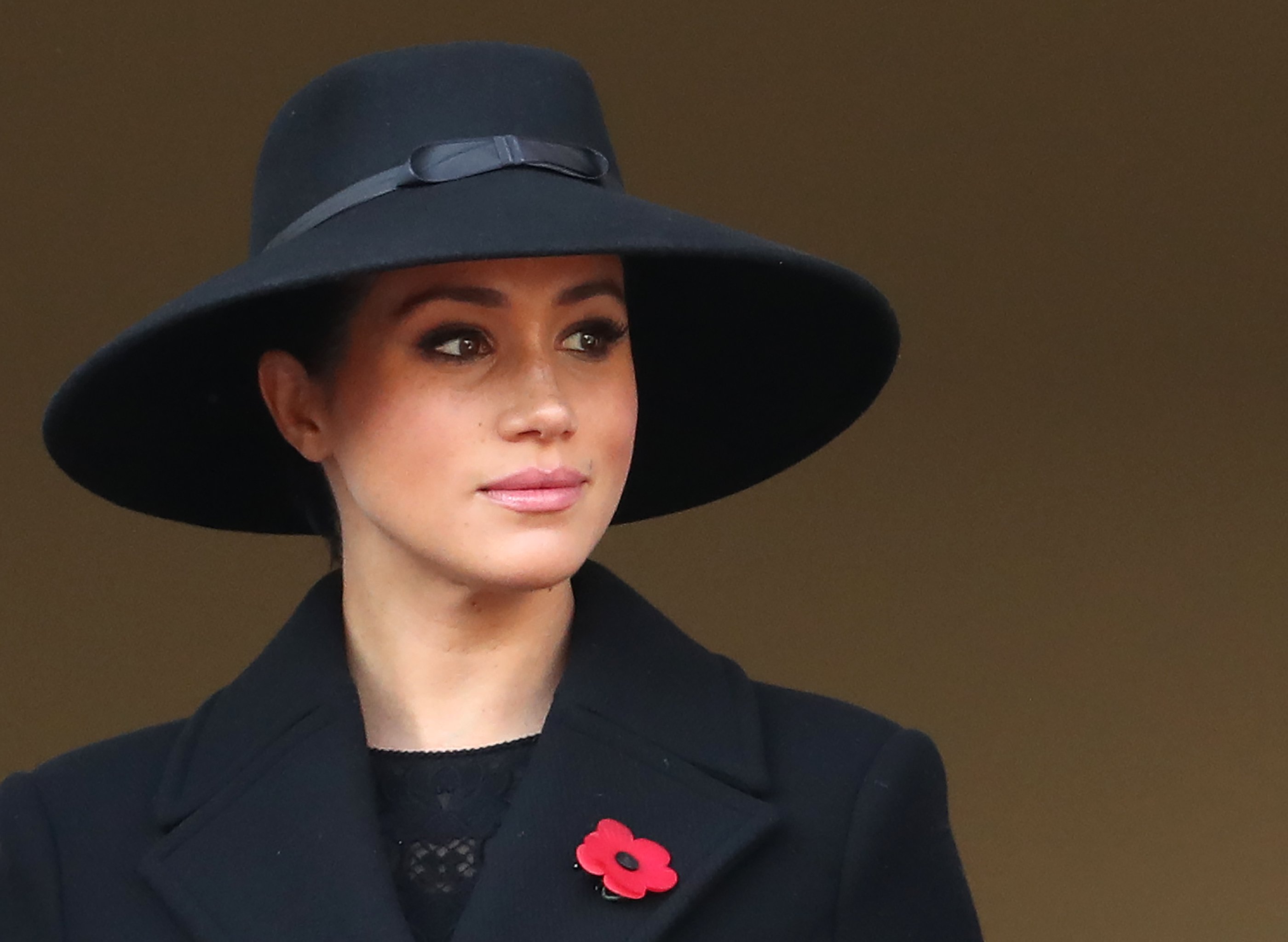 Meghan Markle is dressed in a black hat and coat.