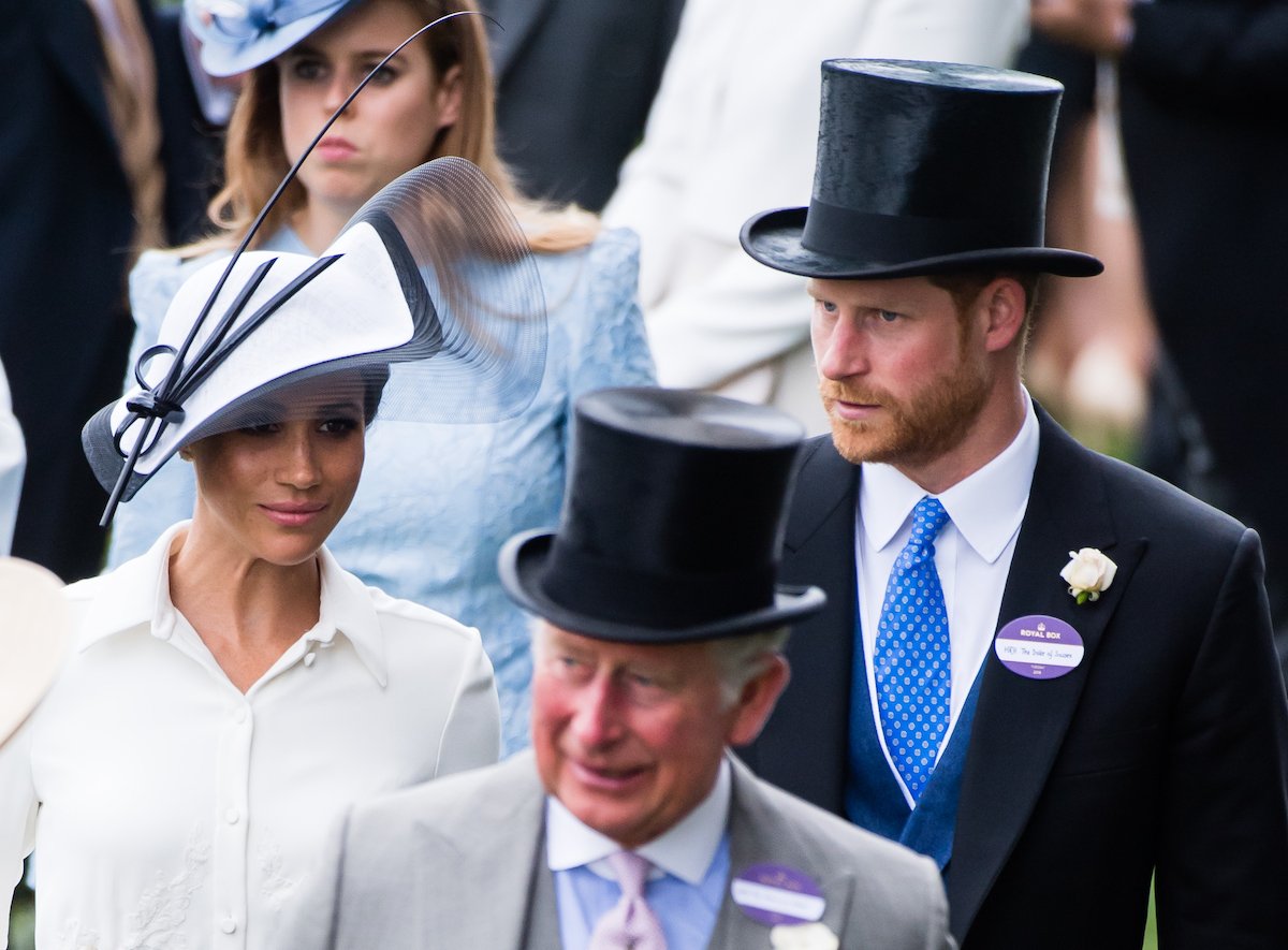 Meghan Markle, Prince Harry, and King Charles, who had four words to describe Meghan Markle after meeting her — 'completely charming, absolutely delightful' — according to Christopher Andersen's 2022 King Charles III biography, walk together in 2018