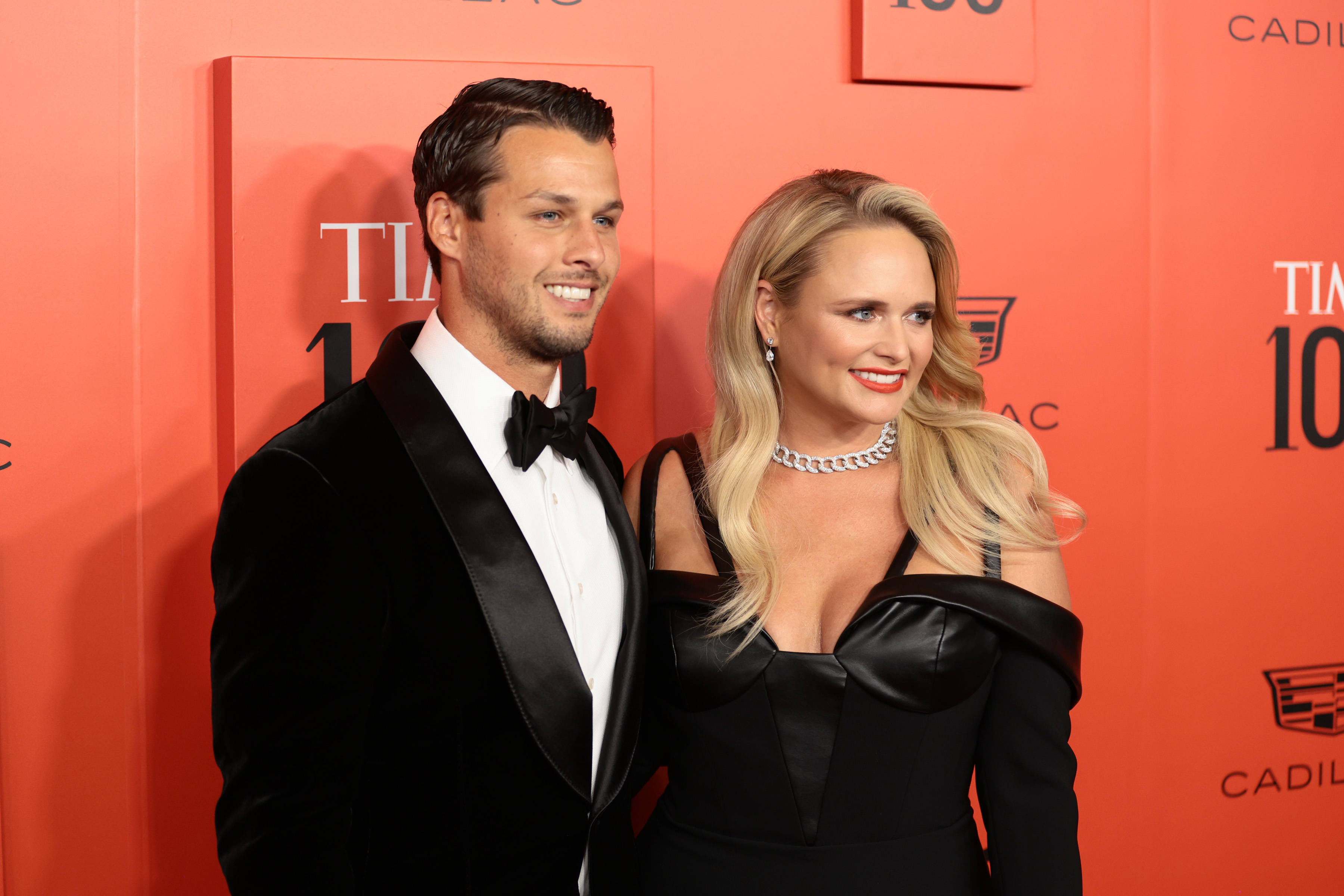 Brendan McLoughlin and Miranda Lambert wear formal black attire in front of a red 'Time 100' backdrop