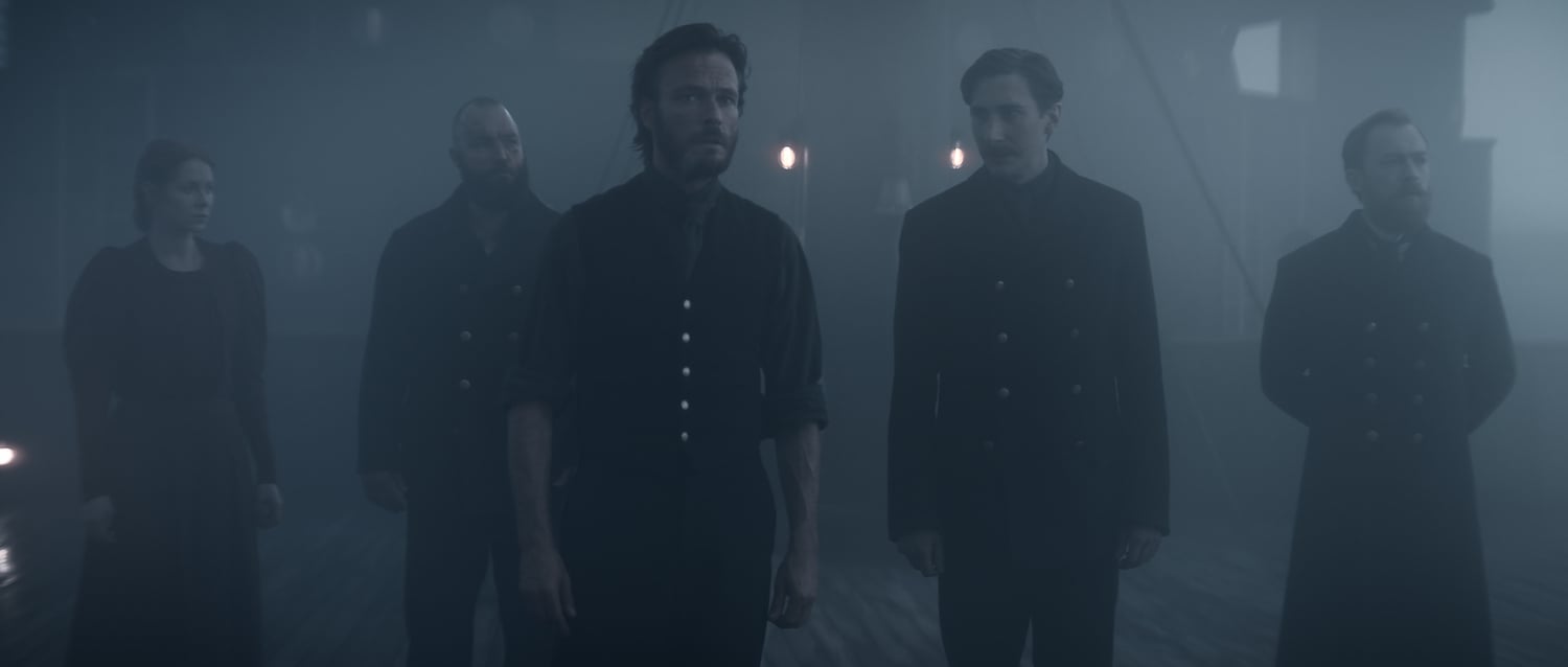 A production still from '1899' showing Emily Beecham, Isaak Dentler, Andreas Pietschmann, Niklas Maienschein, and Tino Mewes stand on a ship at night surrounded by fog.