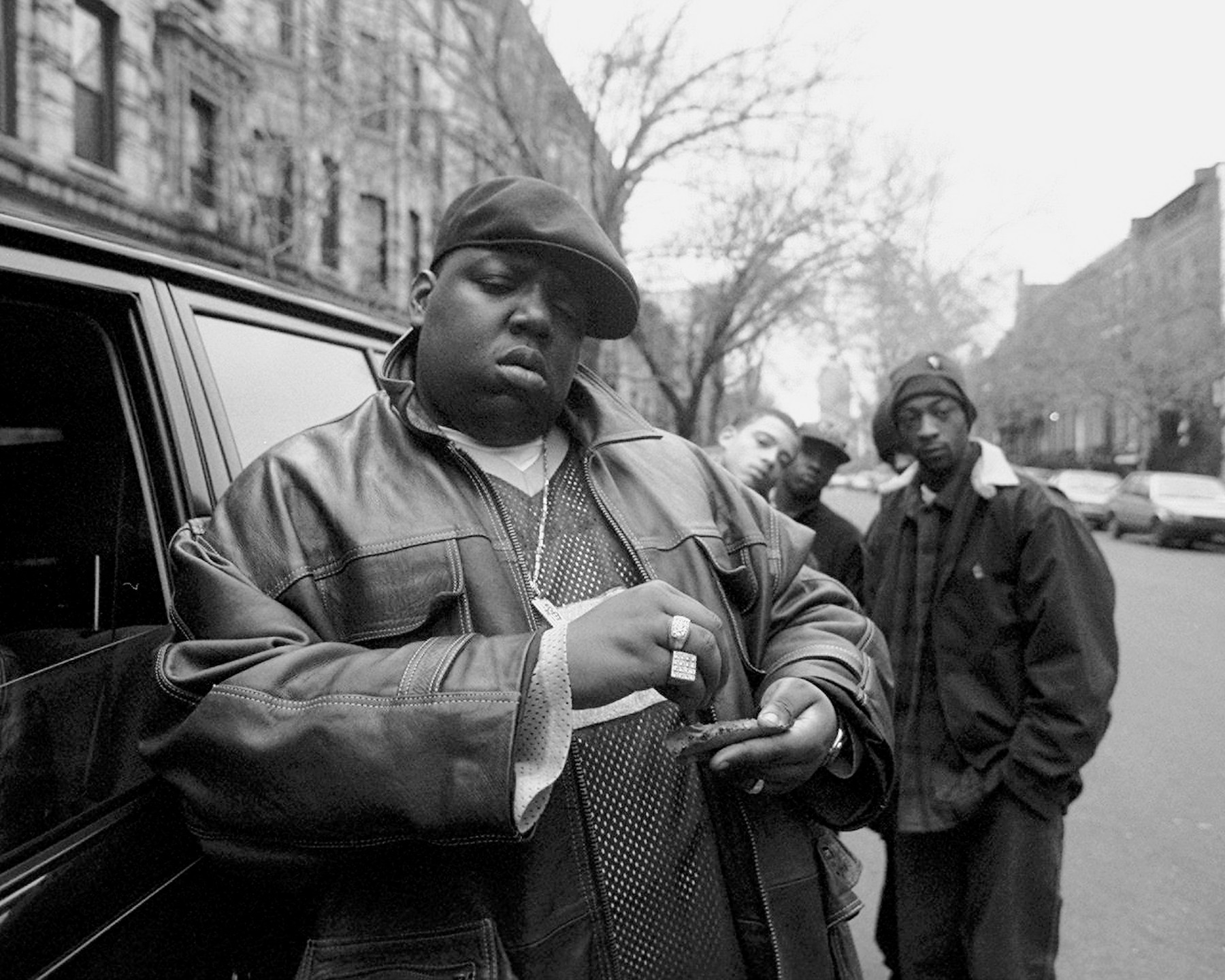 The Notorious B.I.G., real name Christopher Wallace, posing for a photo next to a car