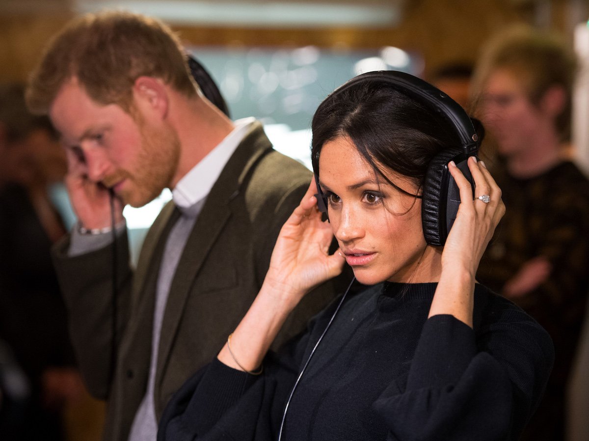 Prince Harry and Meghan Markle, whose 'Archetypes' podcast probably won't have as many listeners as Kim Kardashian's 'The System', use headphones during a visit to a radio station