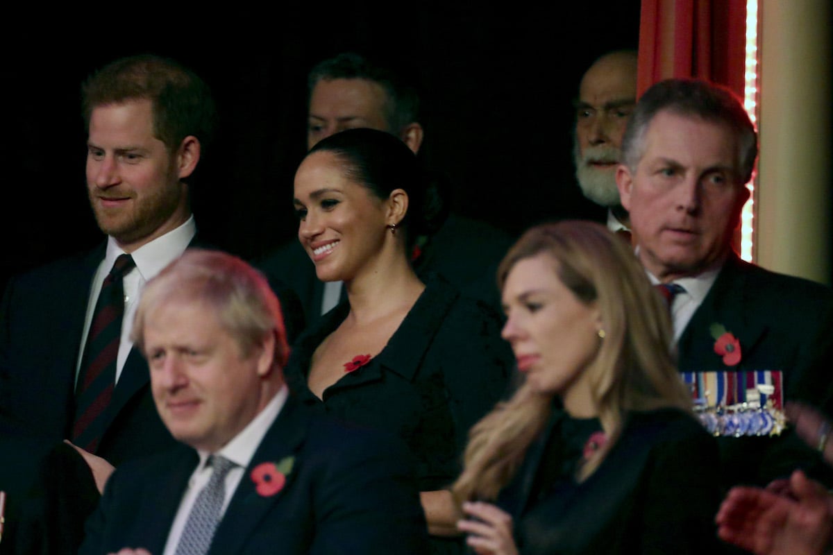 Prince Harry and Meghan Markle, who didn't appear 'happier' than Kate Middleton and Prince William at the 2019 Festival of Remembrance, according to a body language expert, smile sitting at Albert Hall