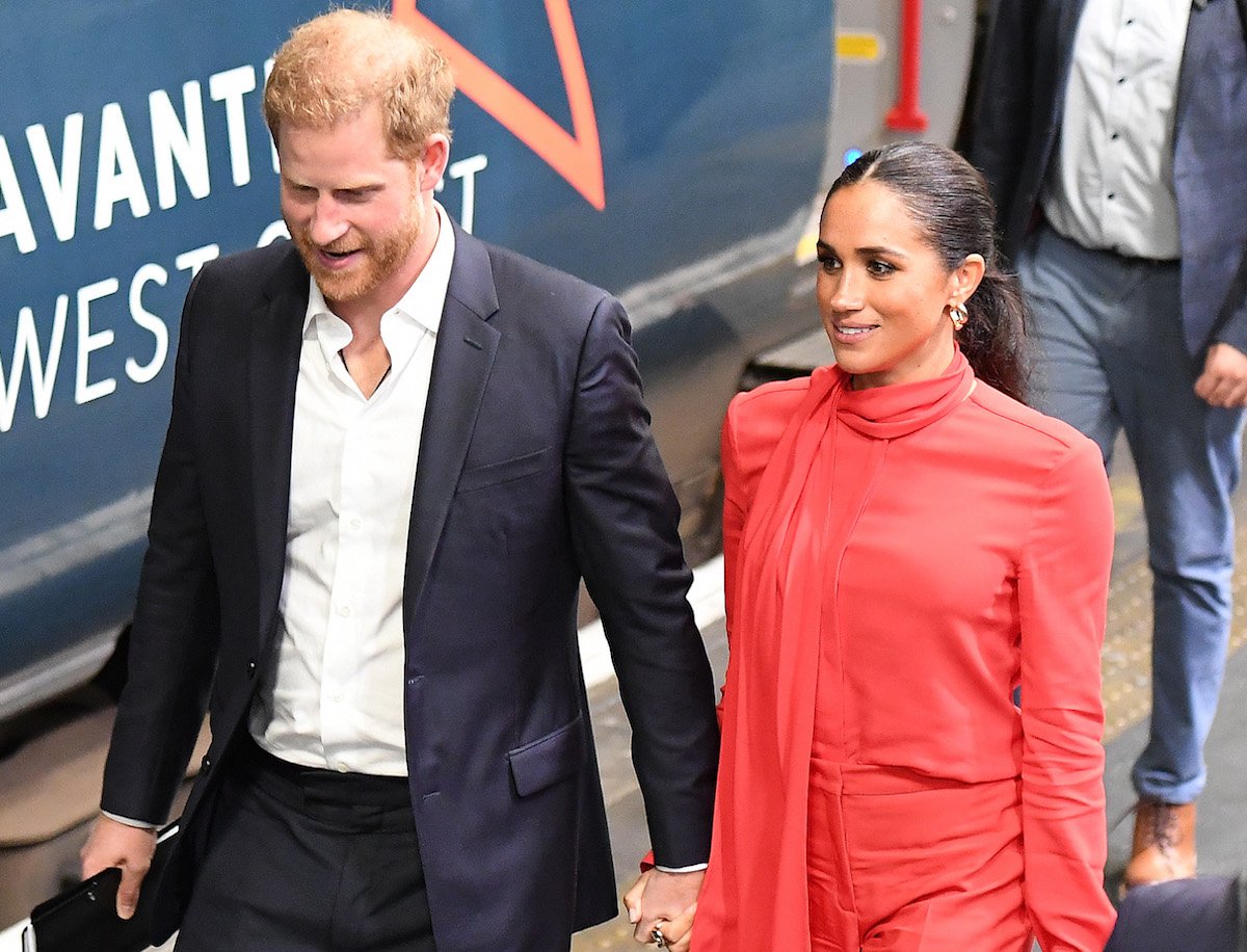 Prince Harry and Meghan Markle, who would 'dampen' the royal family's plans for Christmas at Sandringham by attending, according to royal biographer Angela Levin, hold hands in September 2022
