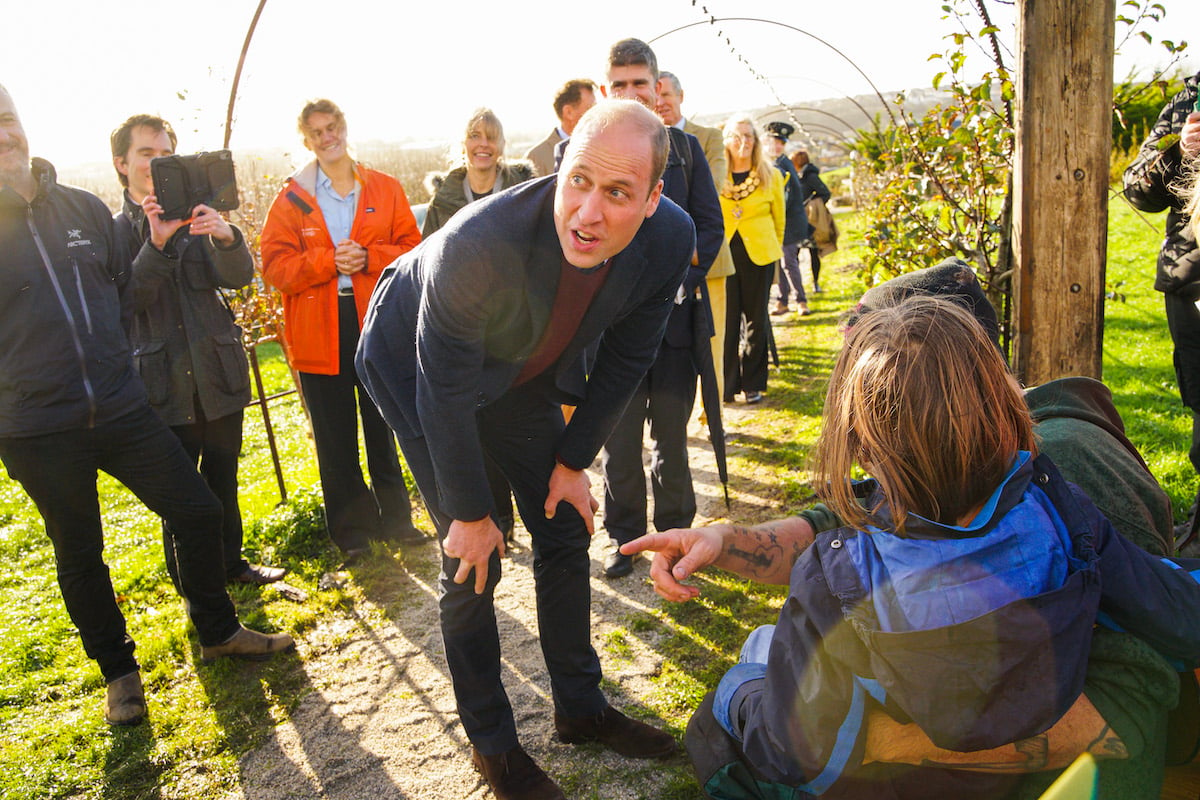 Prince William, who admitted Prince George, Princess Charlotte, and Prince Louis are the reason he drinks lots of tea during a Nov. 24 visit to Cornwall, bends forward to speak to people at Newquay Orchard