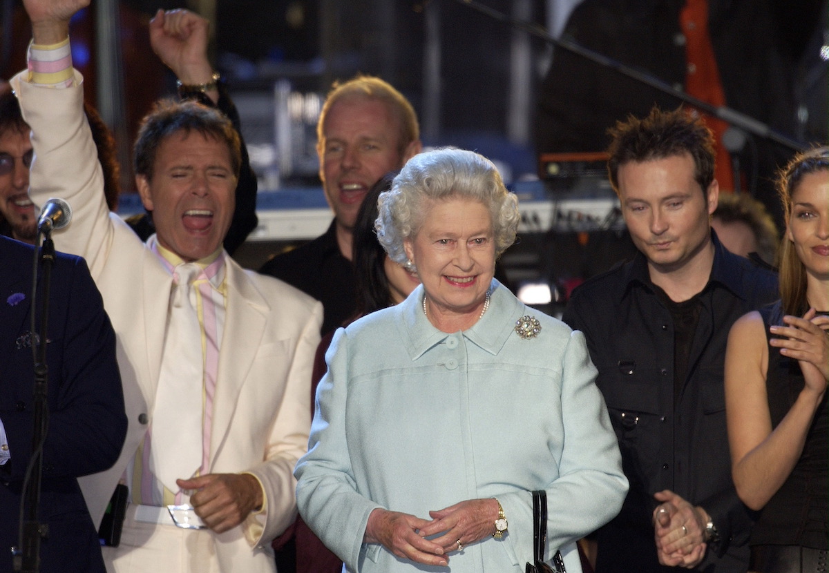 Queen Elizabeth II, who refused to hold a sword in her 2002 Golden Jubilee portrait because she didn't like her hands, according to Rankin, smiles standing on stage during 2002 Party at the Palace