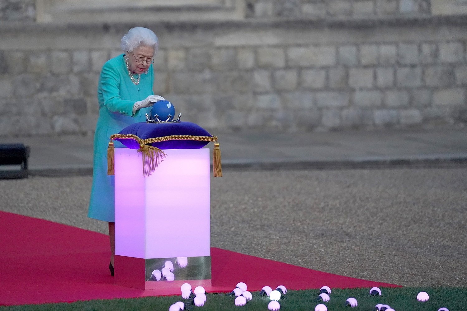 Queen Elizabeth II touches the Commonwealth Nations Globe to start the lighting of the Principal Beacon outside of Buckingham Palace in London