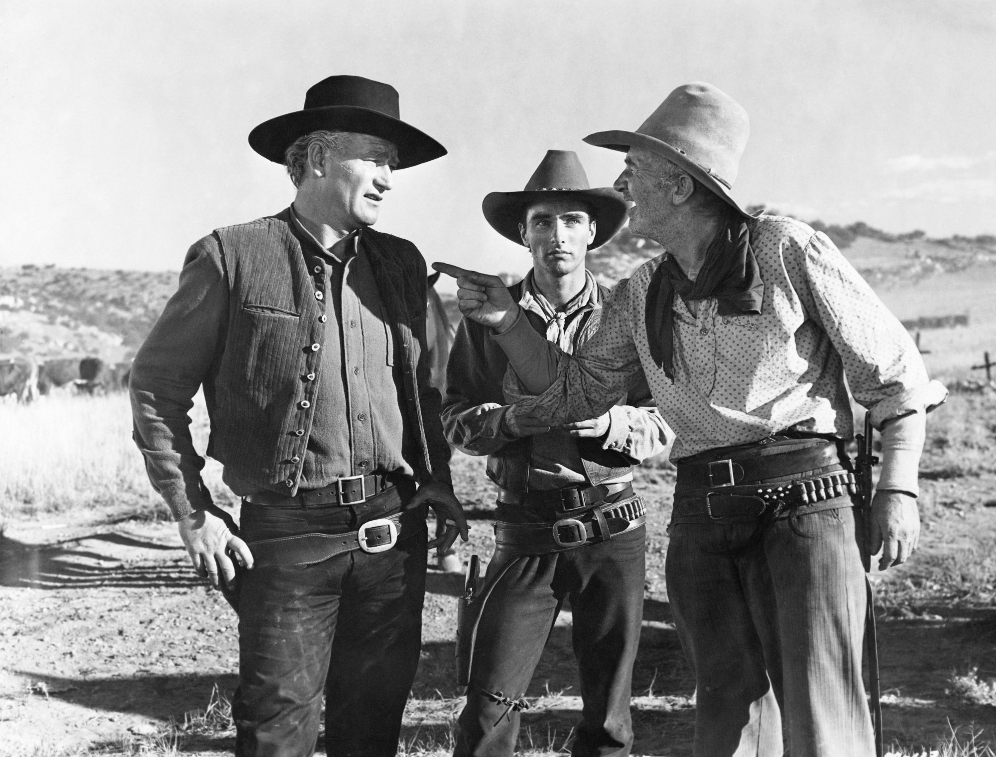 'Red River' John Wayne as Thomas Dunson, Montgomery Clift as Matthew Garth and Walter Brennan as Groot Nadine in a black-and-white picture. Brennan is pointing at Wayne, while Clift is staring at them from behind.