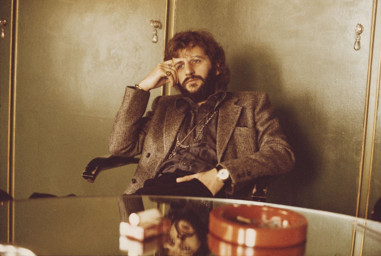 Ringo Starr sits at a table with an ashtray. 