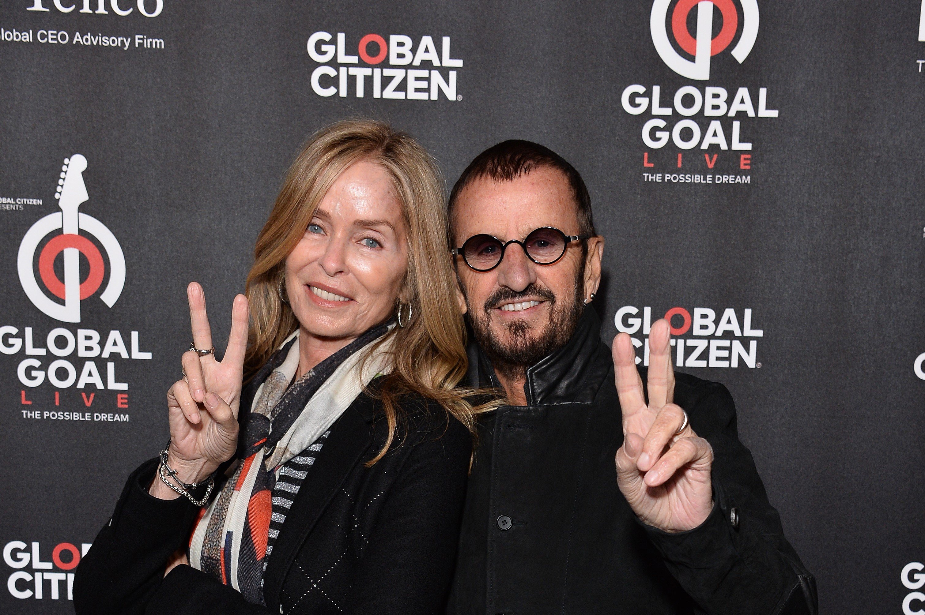 Barbara Bach and Ringo Starr hold up peace signs.