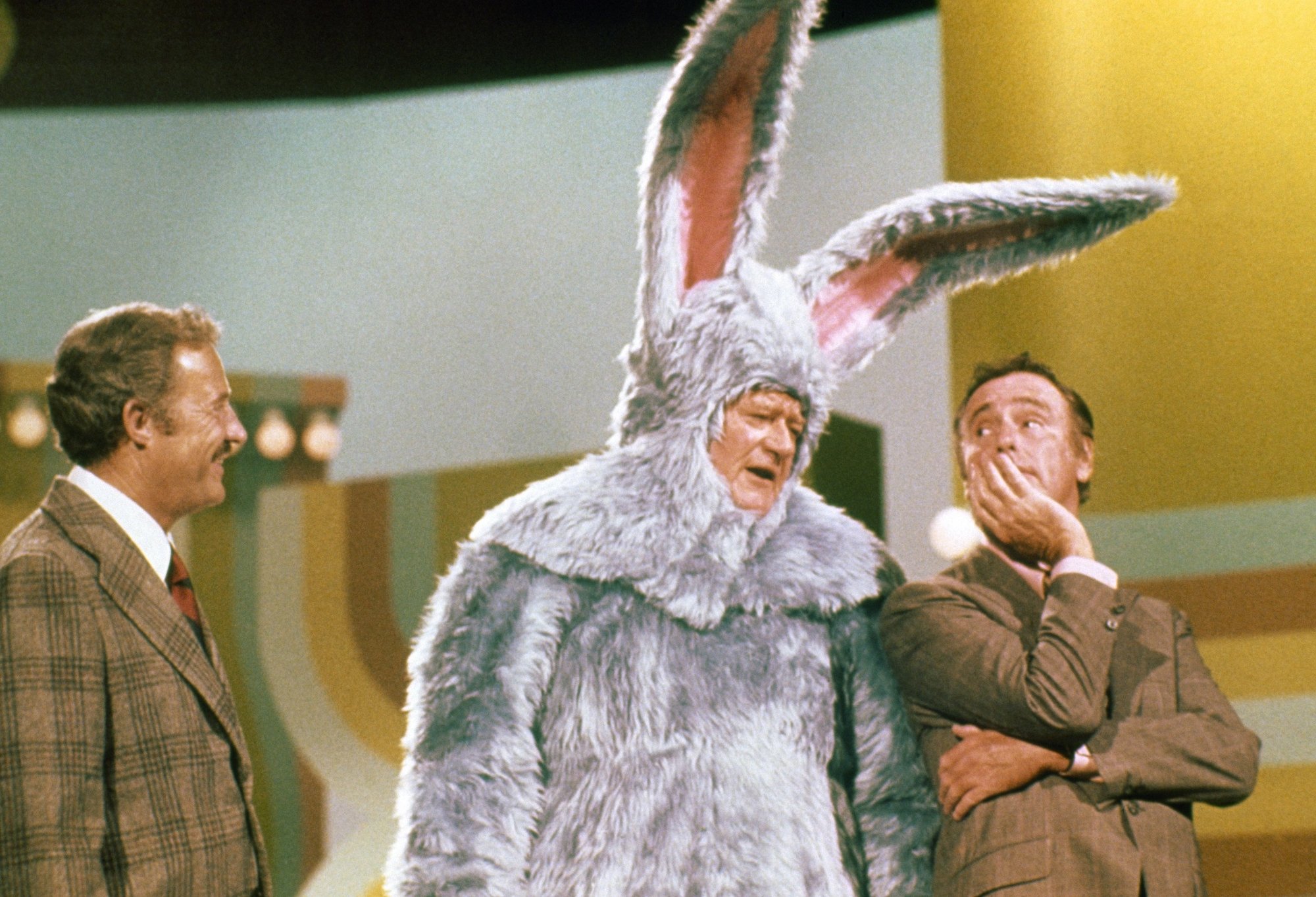 'Rowan and Martin's Laugh-In' Dan Rowan, John Wayne dressed as a bunny, and Dick Martin. The hosts are looking at Wayne, who is mid-speech in the costume.