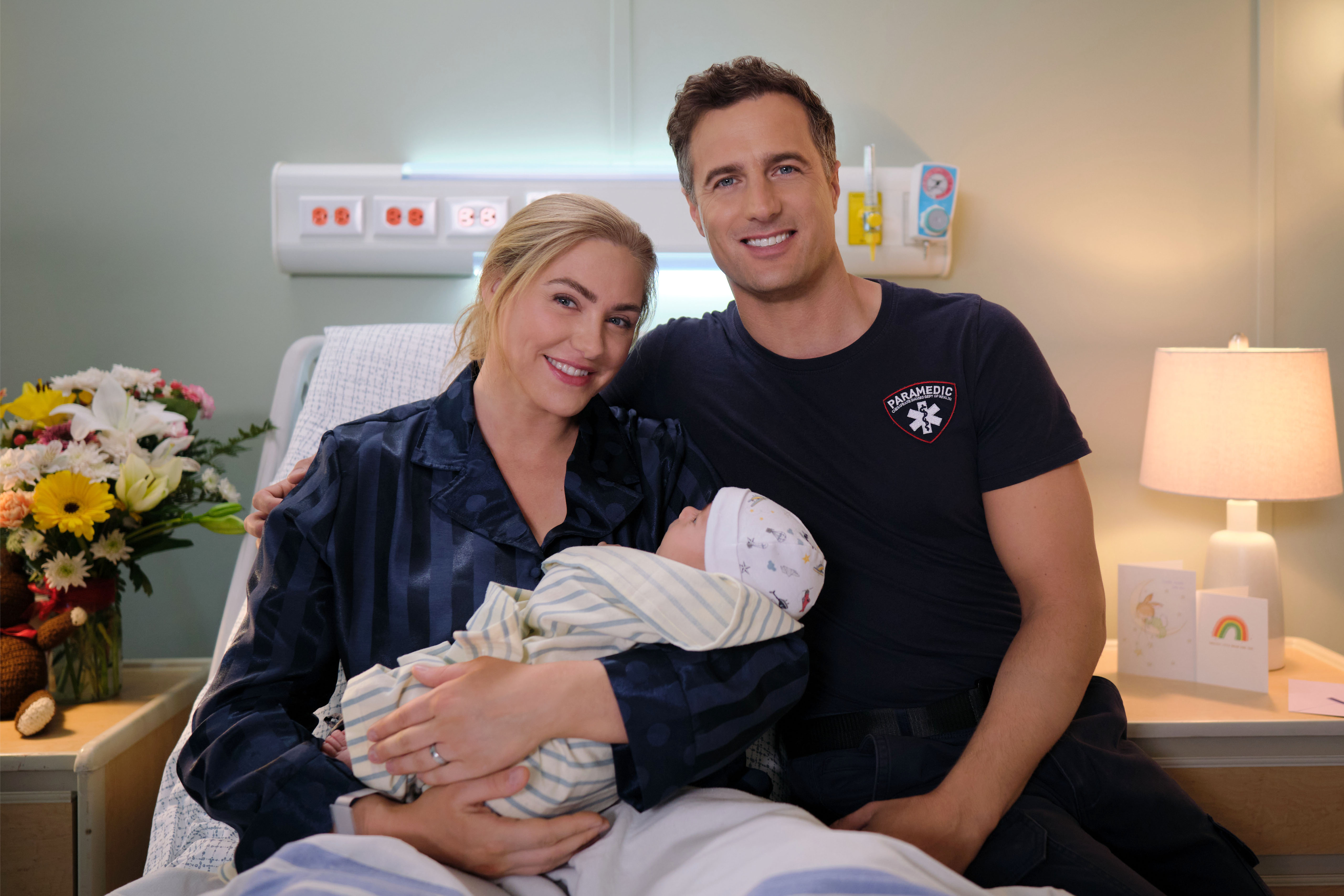Sarah, holding baby, in a hospital bed with Kevin sitting next to her in 'Chesapeake Shores' Season 6 Episode 10