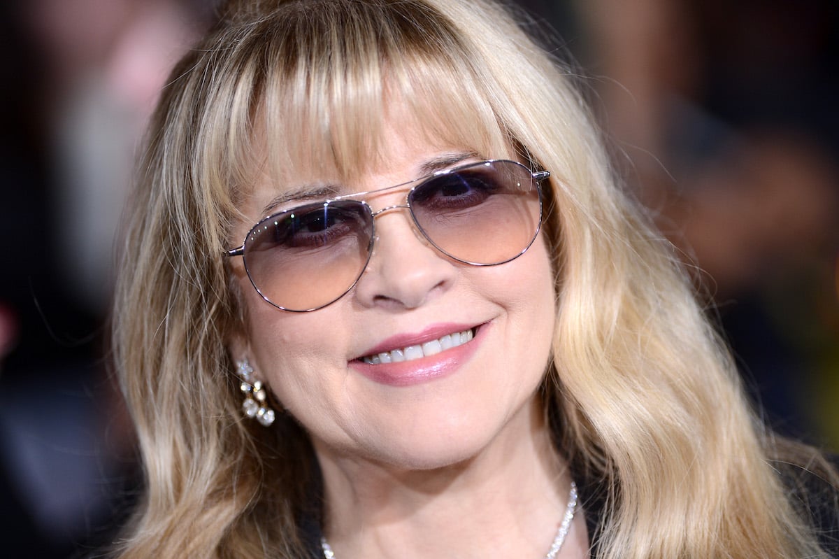 Stevie Nicks, singer for the band Fleetwood Mac, wears sunglasses and smiles at an event.