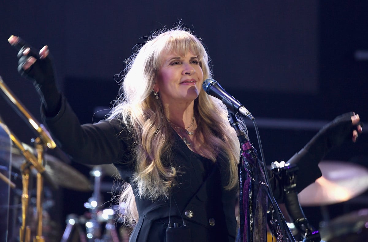 Stevie Nicks, who opened for Jimi Hendrix and Janis Joplin, smiles into a microphone on stage.