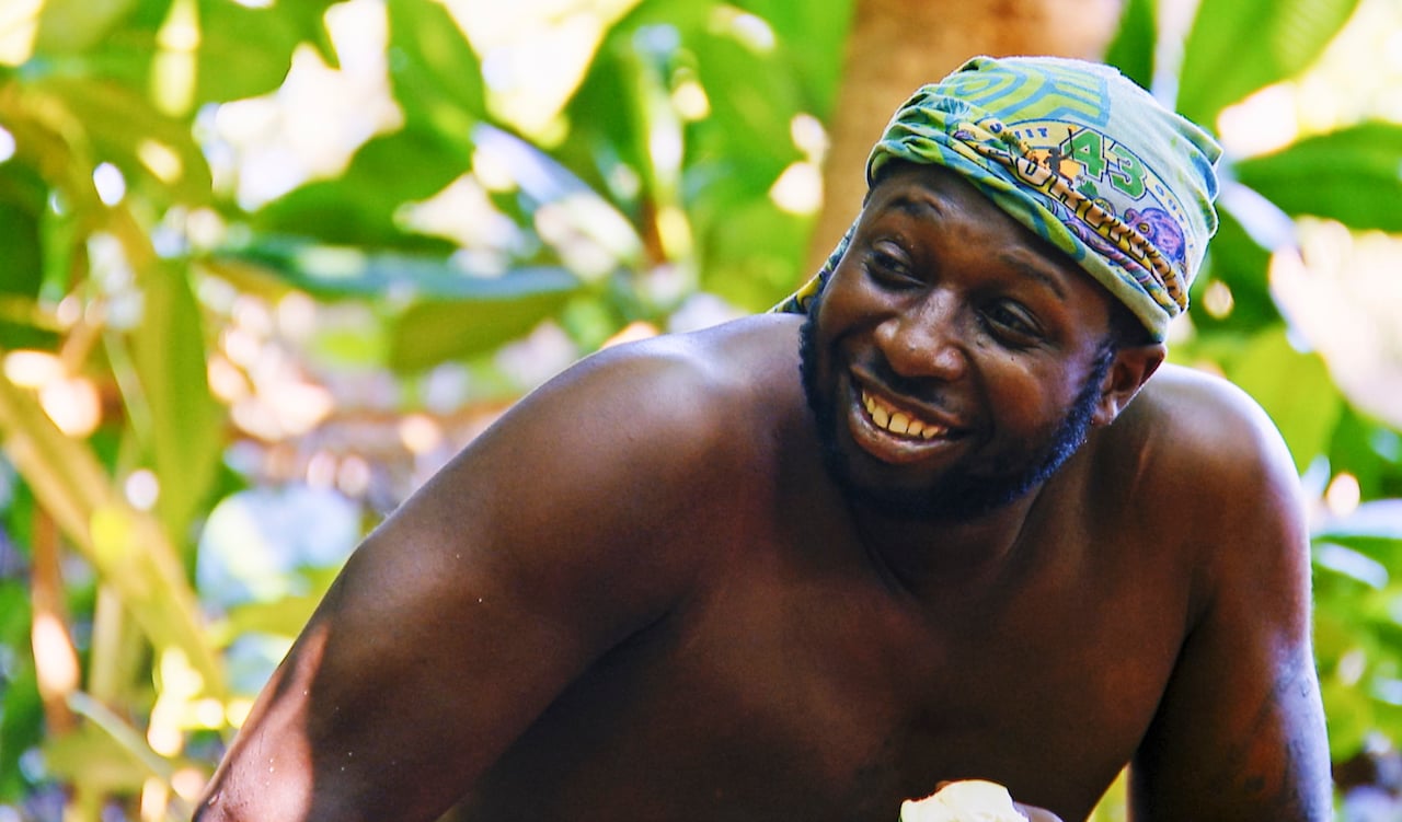 James Jones smiles as he sits in front of trees on 'Survivor 43'.