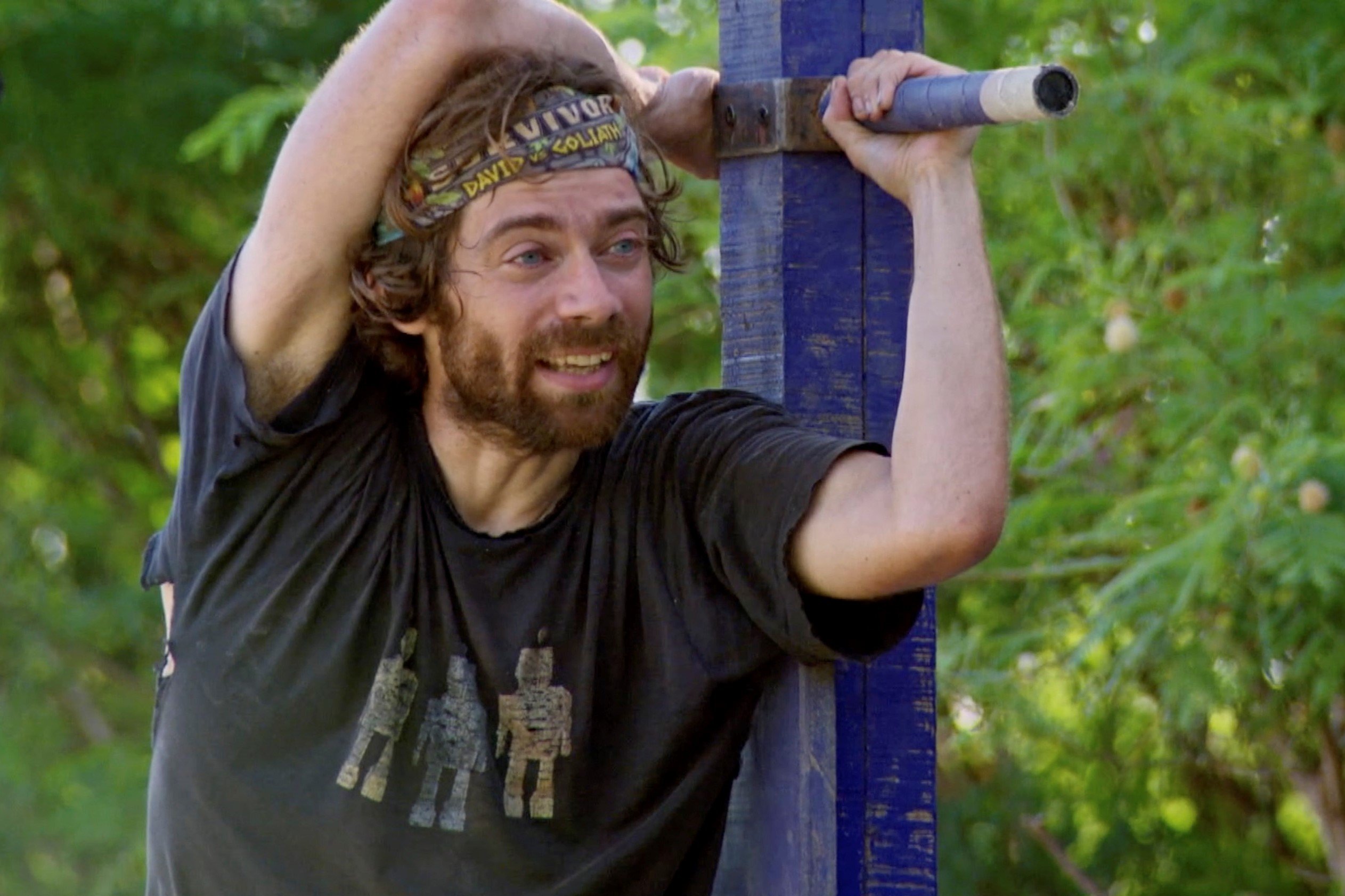 Christian Hubicki, who many fans want to see return to 'Survivor' in an All-Stars season, competes in an immunity challenge wearing a torn black shirt and his 'Survivor' buff.