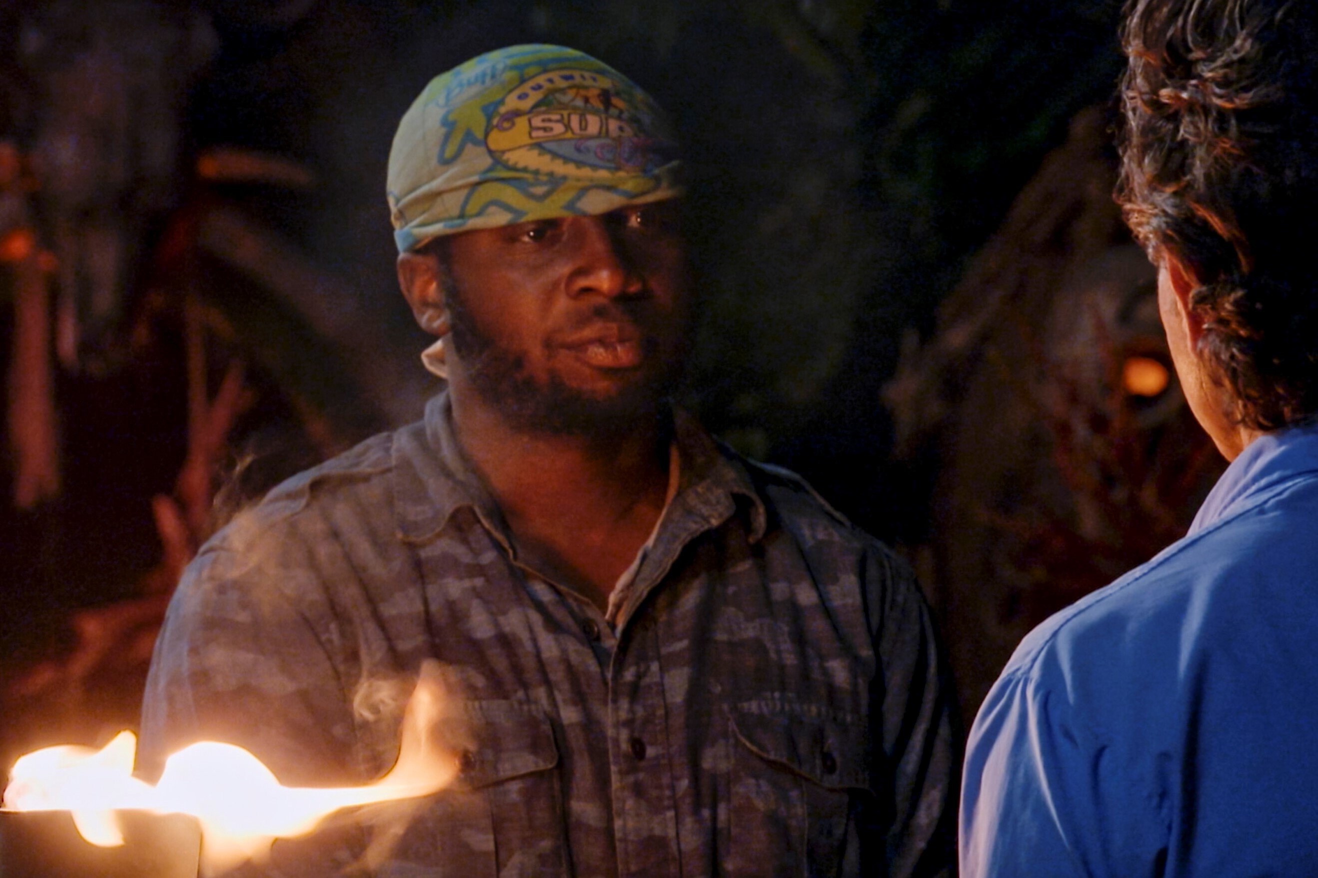 James Jones, who stars in 'Survivor' Season 43 on CBS, gets his torch snuffed by Jeff Probst. James wears a blue camo button-up shirt and his light blue 'Survivor' buff around his head.
