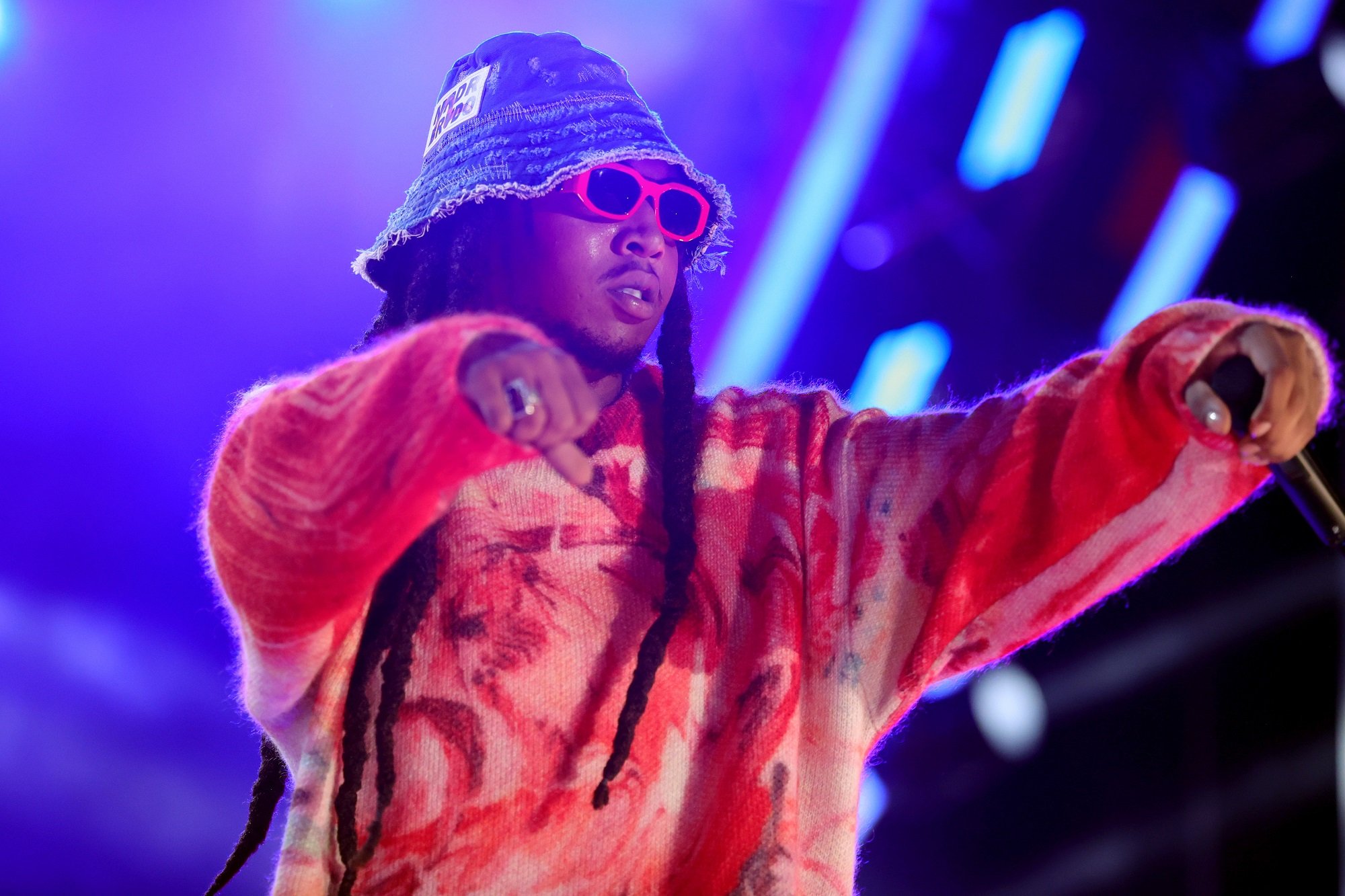 Takeoff performs wearing a denim bucket hat, red sunglasses, and a red sweater