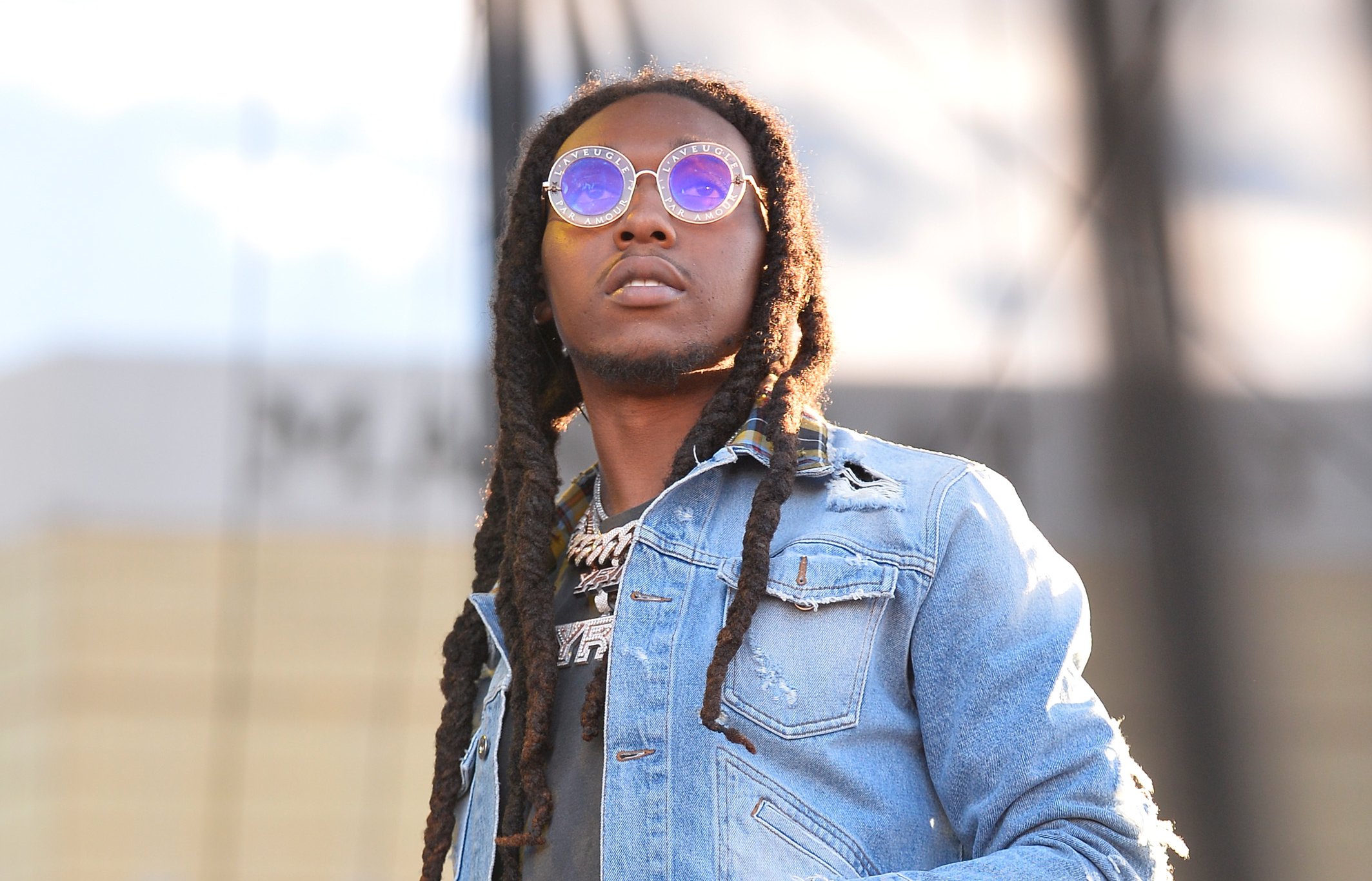 Migos rapper Takeoff, killed in a Nov. 1 shooting, performing on stage in a blue jacket and sunglasses.