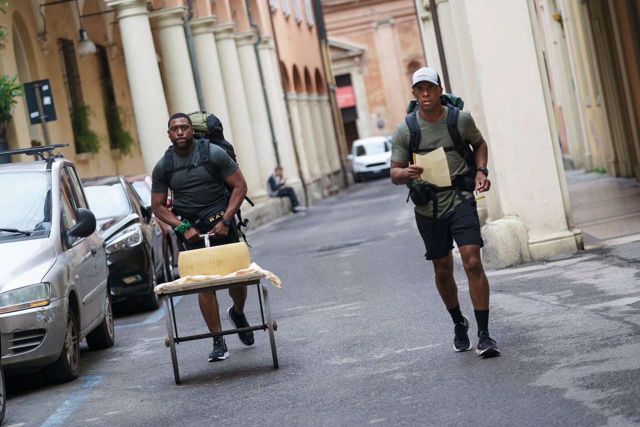 Marcus Craig runs pushing a cart of cheese next to Michael Craig on 'The Amazing Race'.