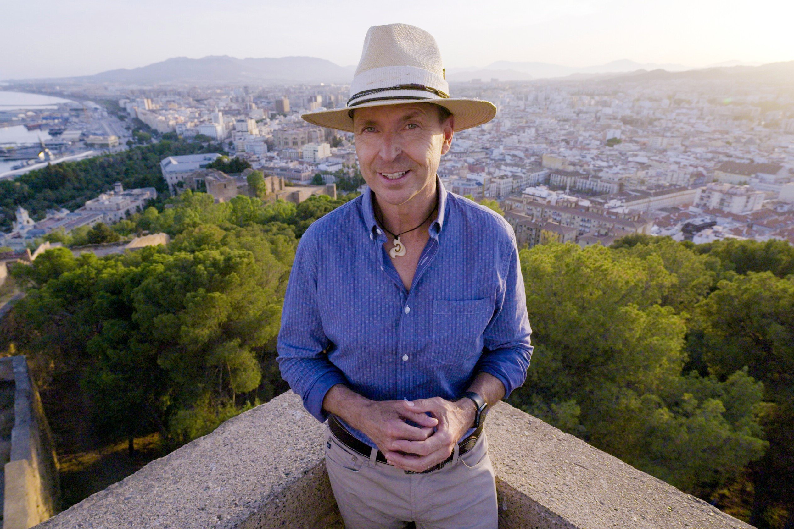 Phil Keoghan, who, according to spoilers, will host 'The Amazing Race 35' on CBS, wears a blue patterned button-down shirt, khakis, and a tan hat.