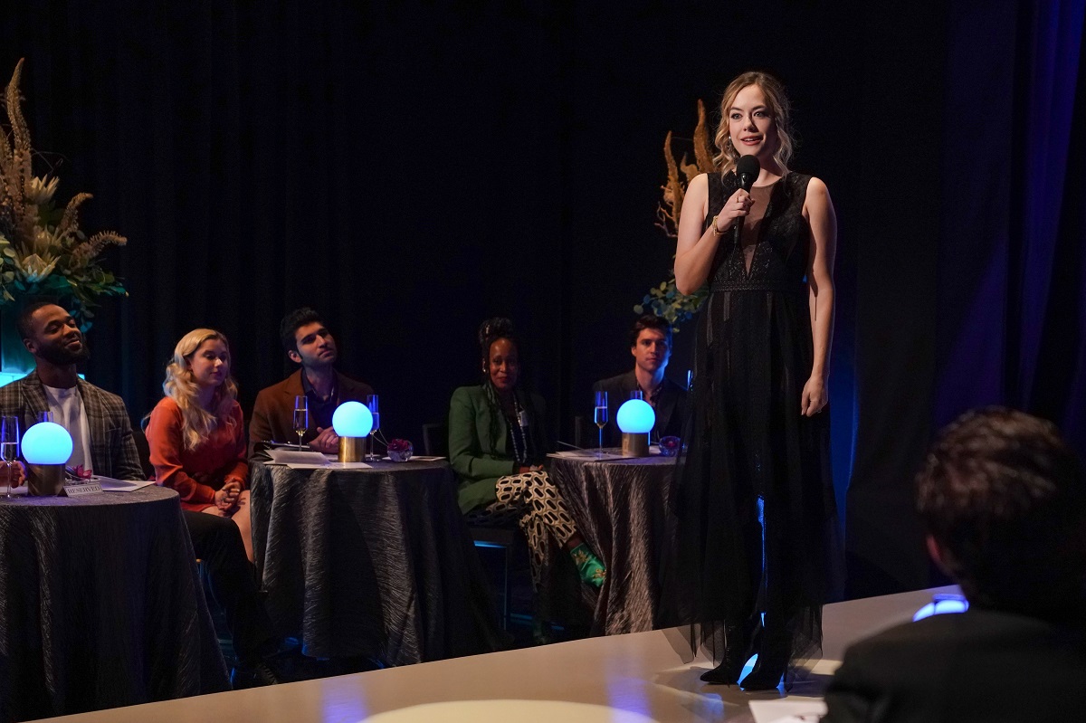 'The Bold and the Beautiful' star Annika Noelle dressed in black stands on a catwalk and holds a microphone.