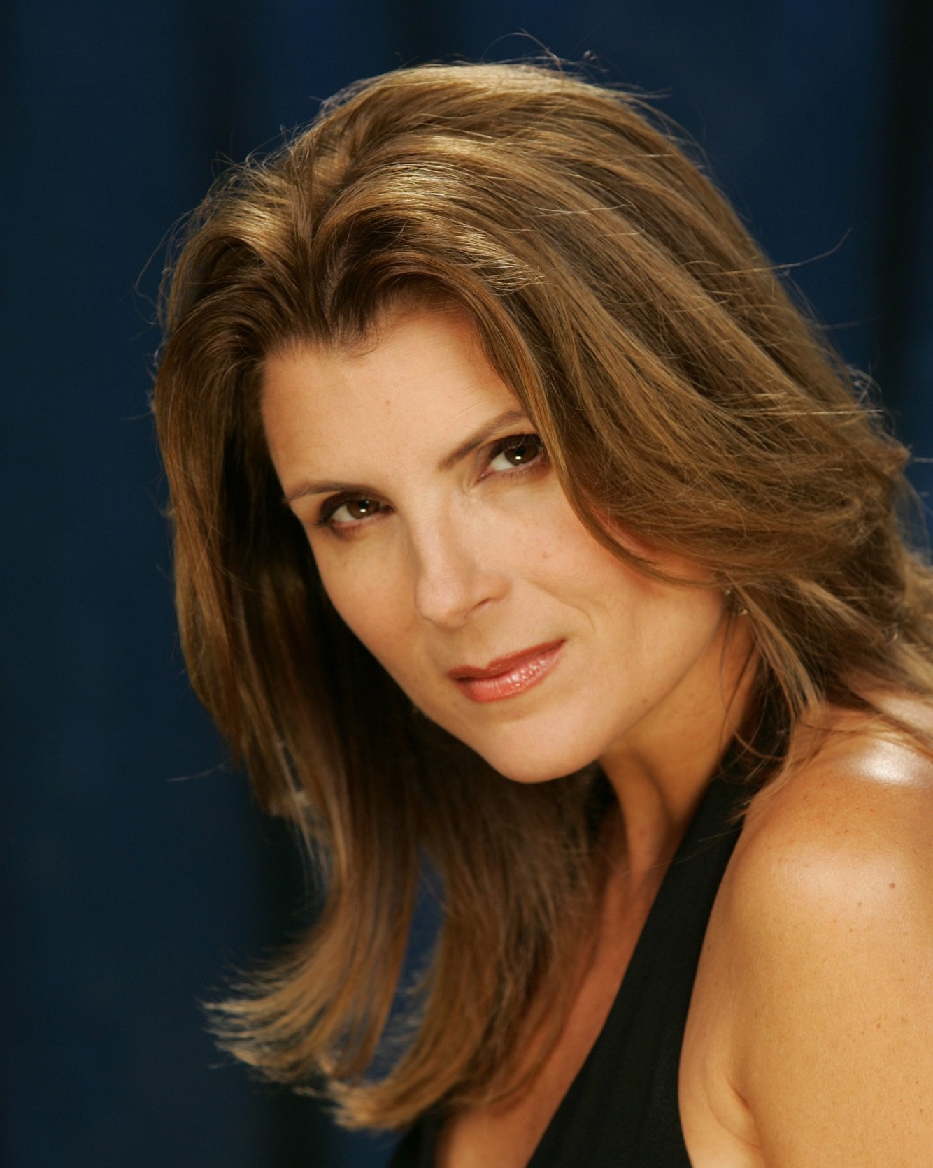 'The Bold and the Beautiful' star Kimberlin Brown wearing a black halter dress and posing in front of a blue backdrop.