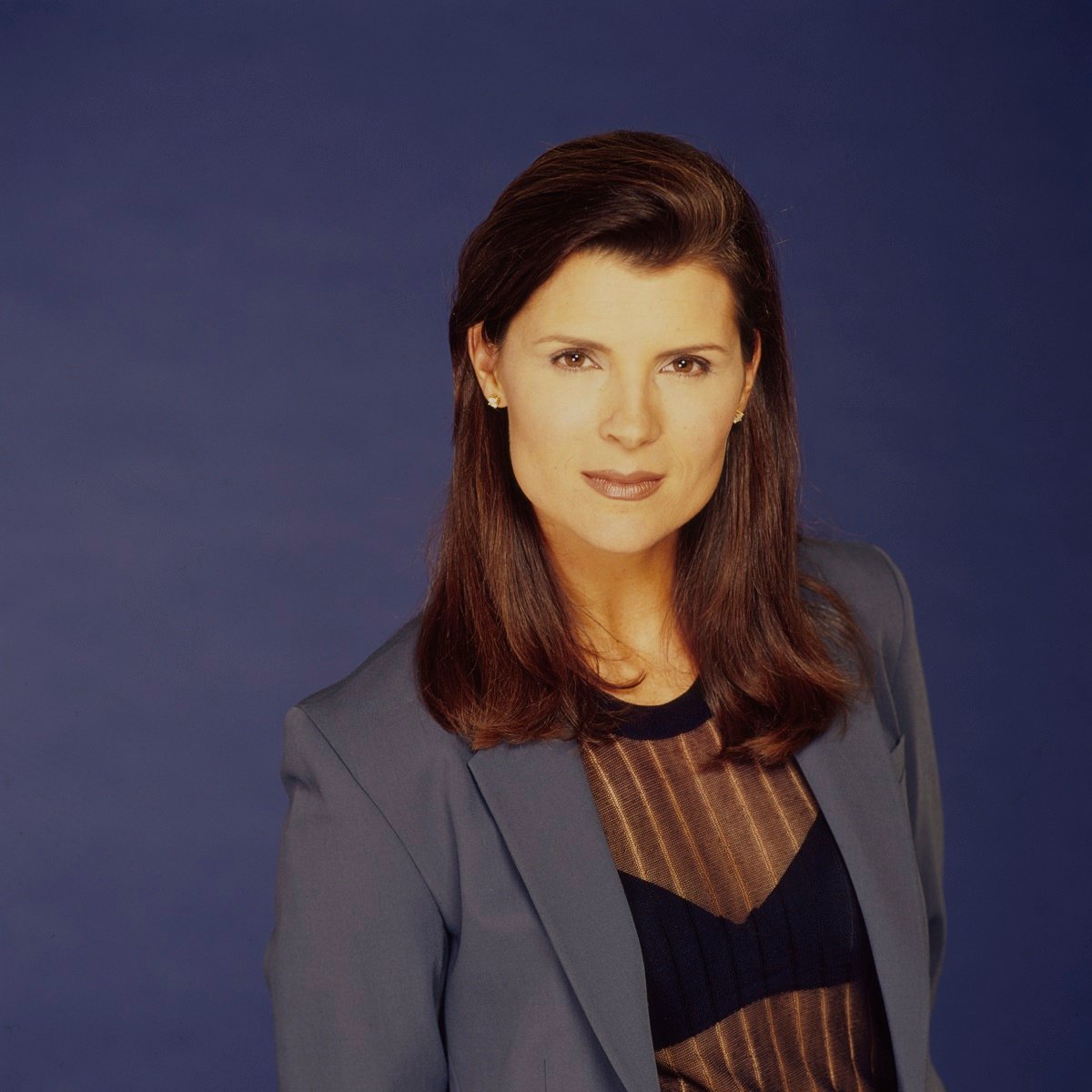 'The Bold and the Beautiful' star Kimberlin Brown wearing a blue suit and posing in front of a blue backdrop.