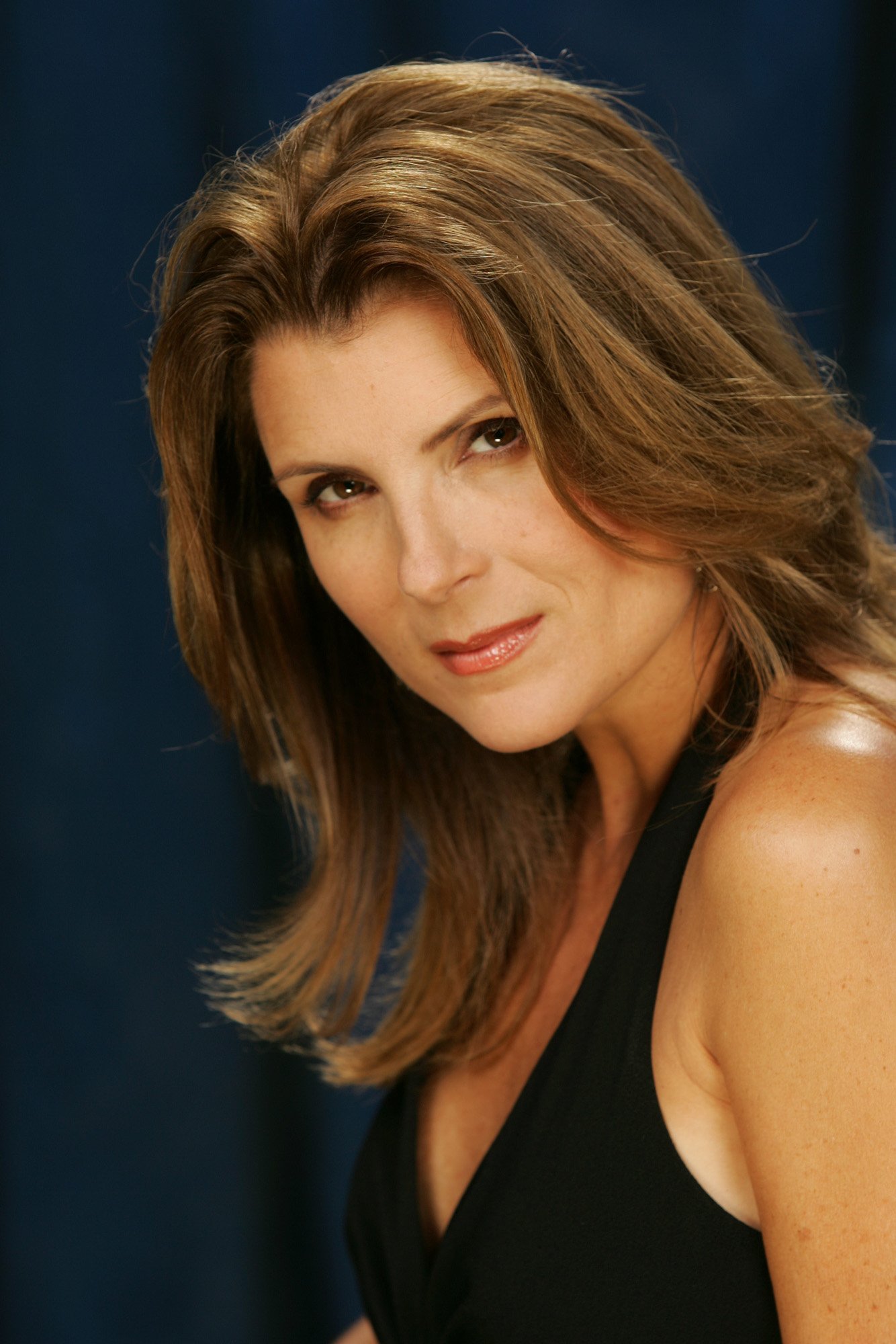 'The Bold and the Beautiful' star Kimberlin Brown wearing a black halter dress and posing in front of a blue backdrop.