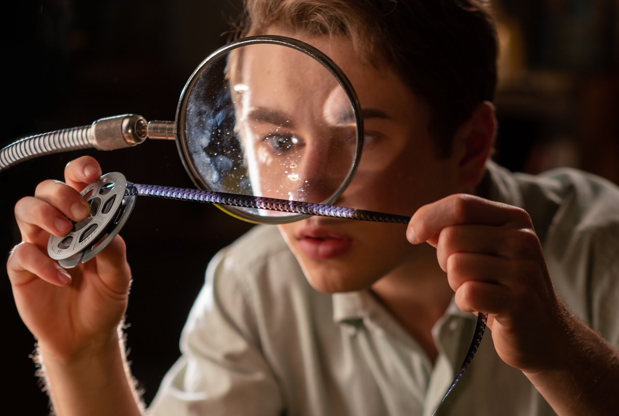 'The Fabelmans' Gabriel LaBelle as Sammy Fabelman looking at a reel of film through a magnifying glass